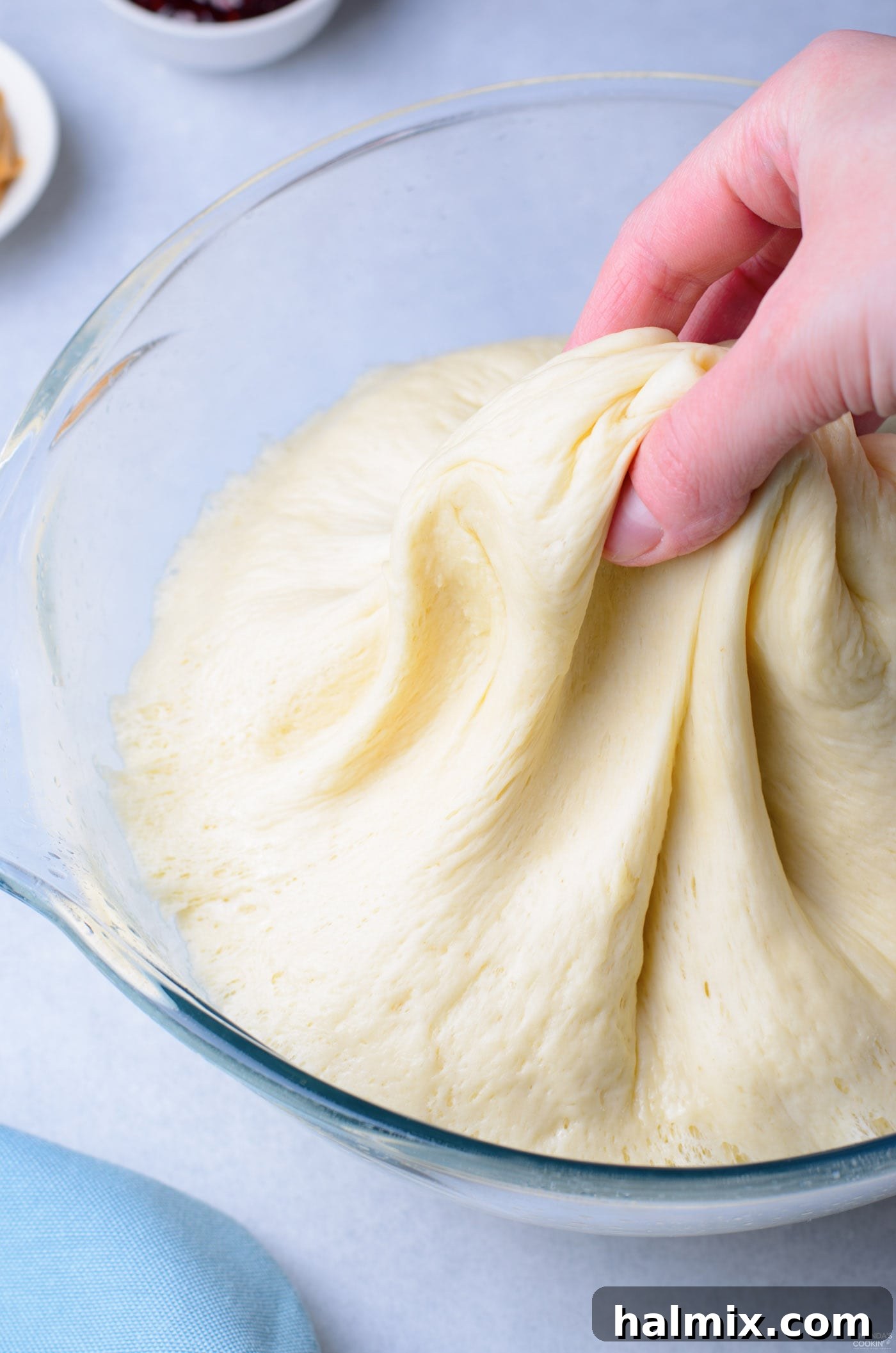 Hands gently pinching and shaping donut dough on a floured surface.