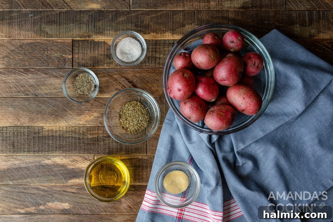 A flat lay photograph displaying all the ingredients required for Air Fryer Roasted Potatoes, including fresh baby red potatoes, olive oil, and various spices.
