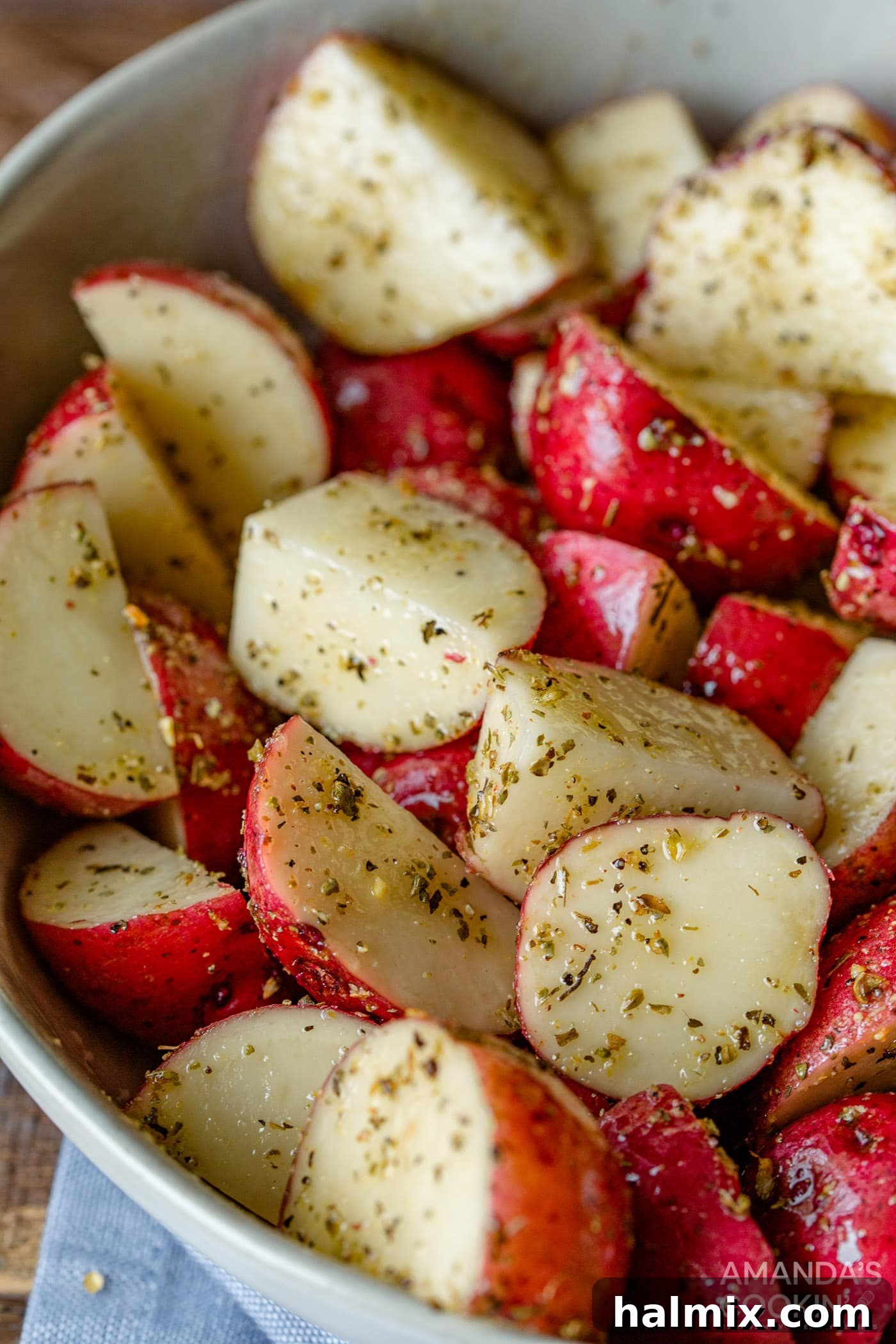 Cubed potatoes in a mixing bowl, generously coated with olive oil and a vibrant blend of seasonings, ready for the air fryer.