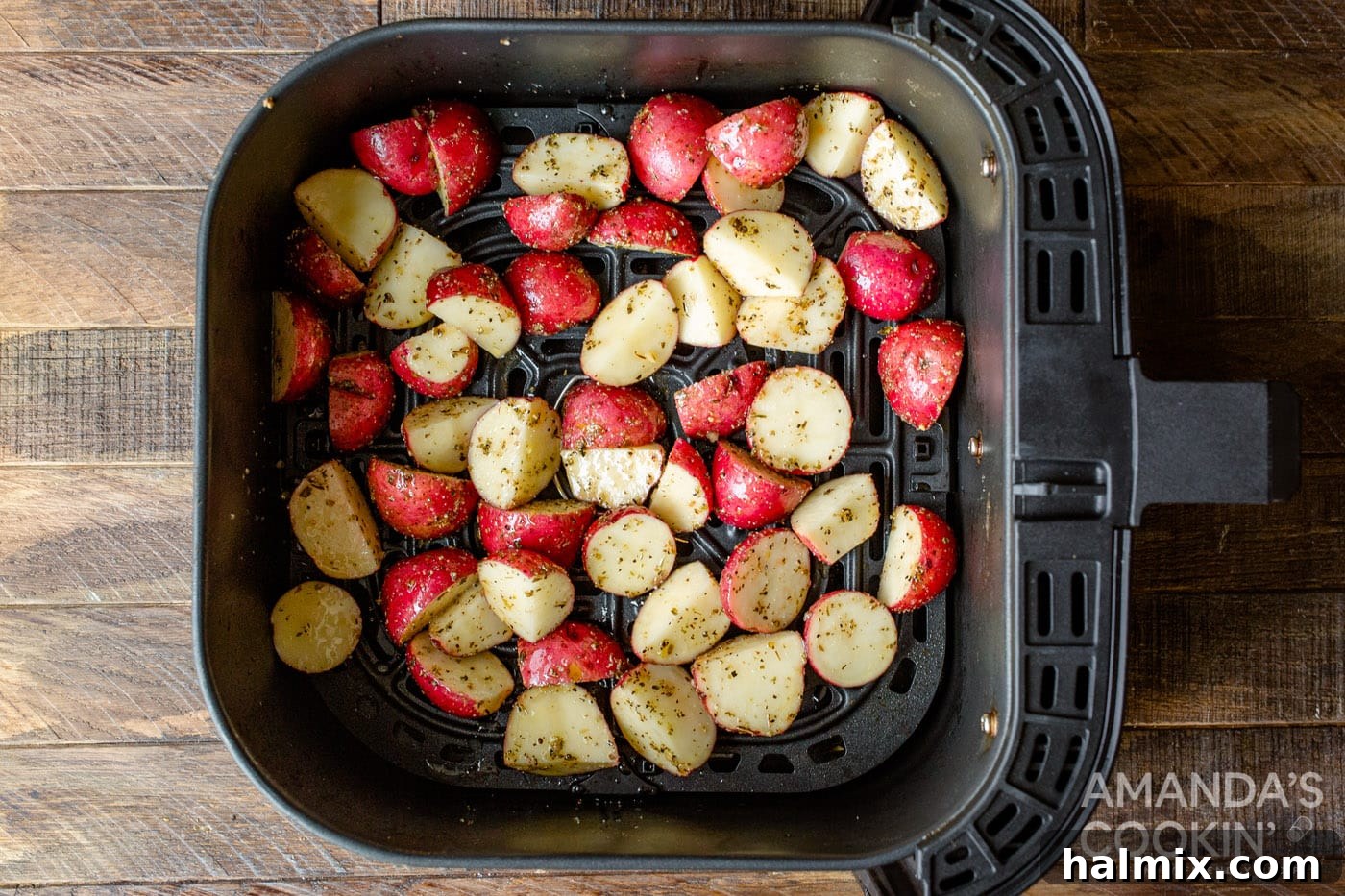 Close-up of seasoned potato cubes arranged in a single layer within an air fryer basket, ready for cooking.
