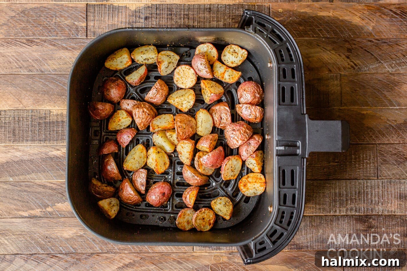 Crispy, golden-brown roasted potatoes visible through the air fryer's viewing window, showcasing their perfect texture and readiness.