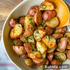 A bowl of freshly air-fried roasted potatoes, garnished with herbs, showcasing a crispy exterior and tender interior.