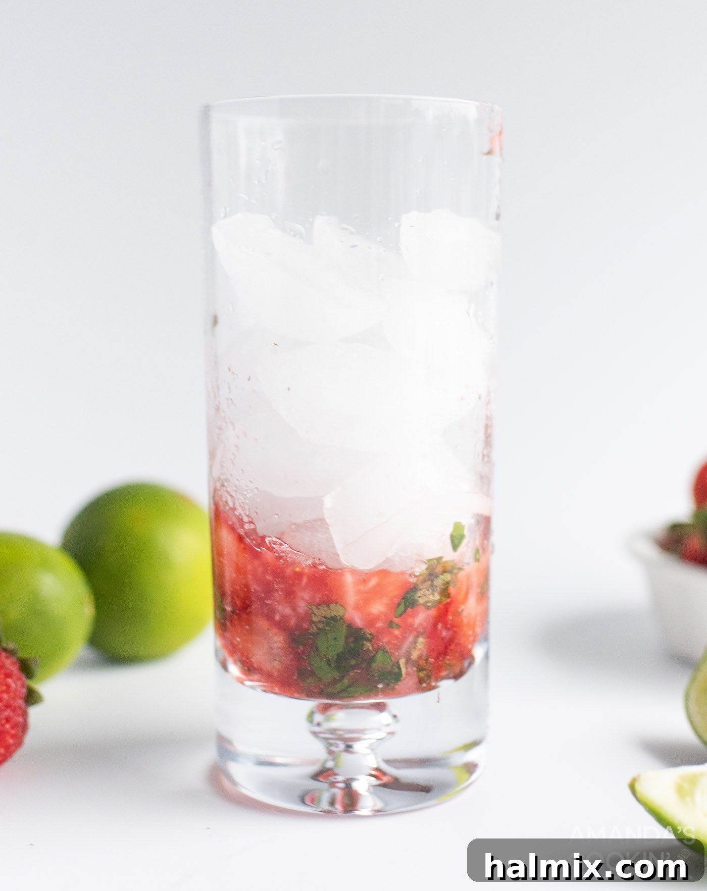 Muddled strawberries and mint with added lime wedges and sugar in a glass