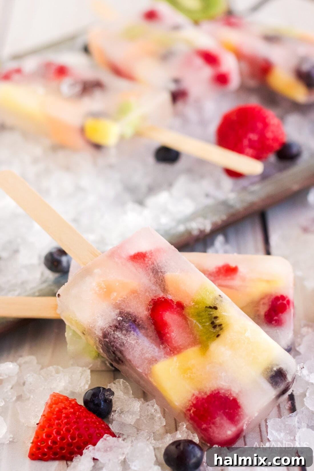 Summer Fruit Delights 8 A variety of fruit popsicles, some still in mold, some removed, on a white background