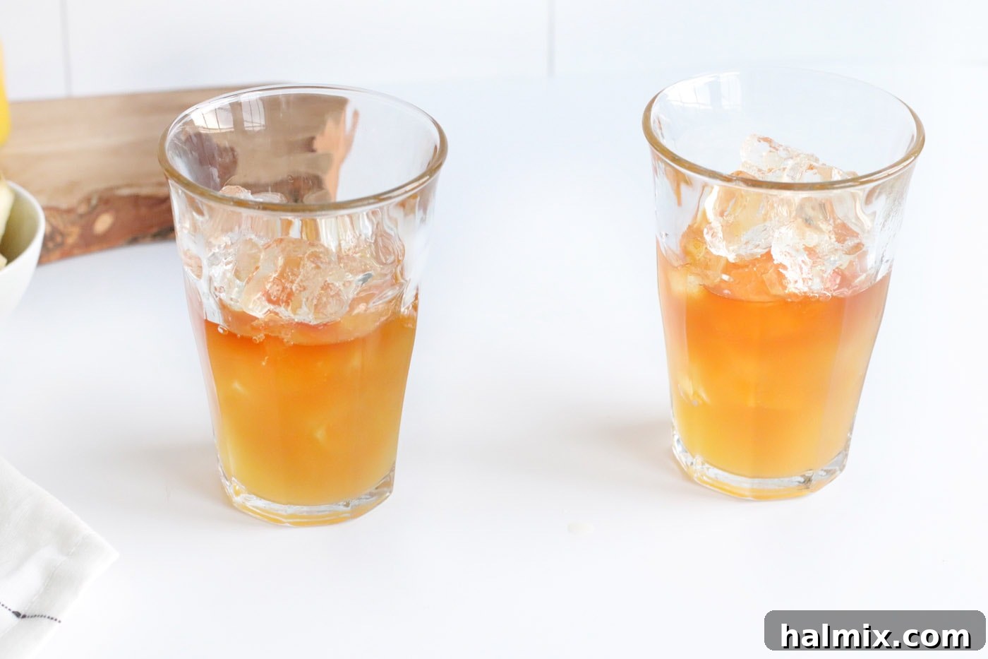 pineapple juice being poured into a glass containing rum and ice, showing the start of color layering.