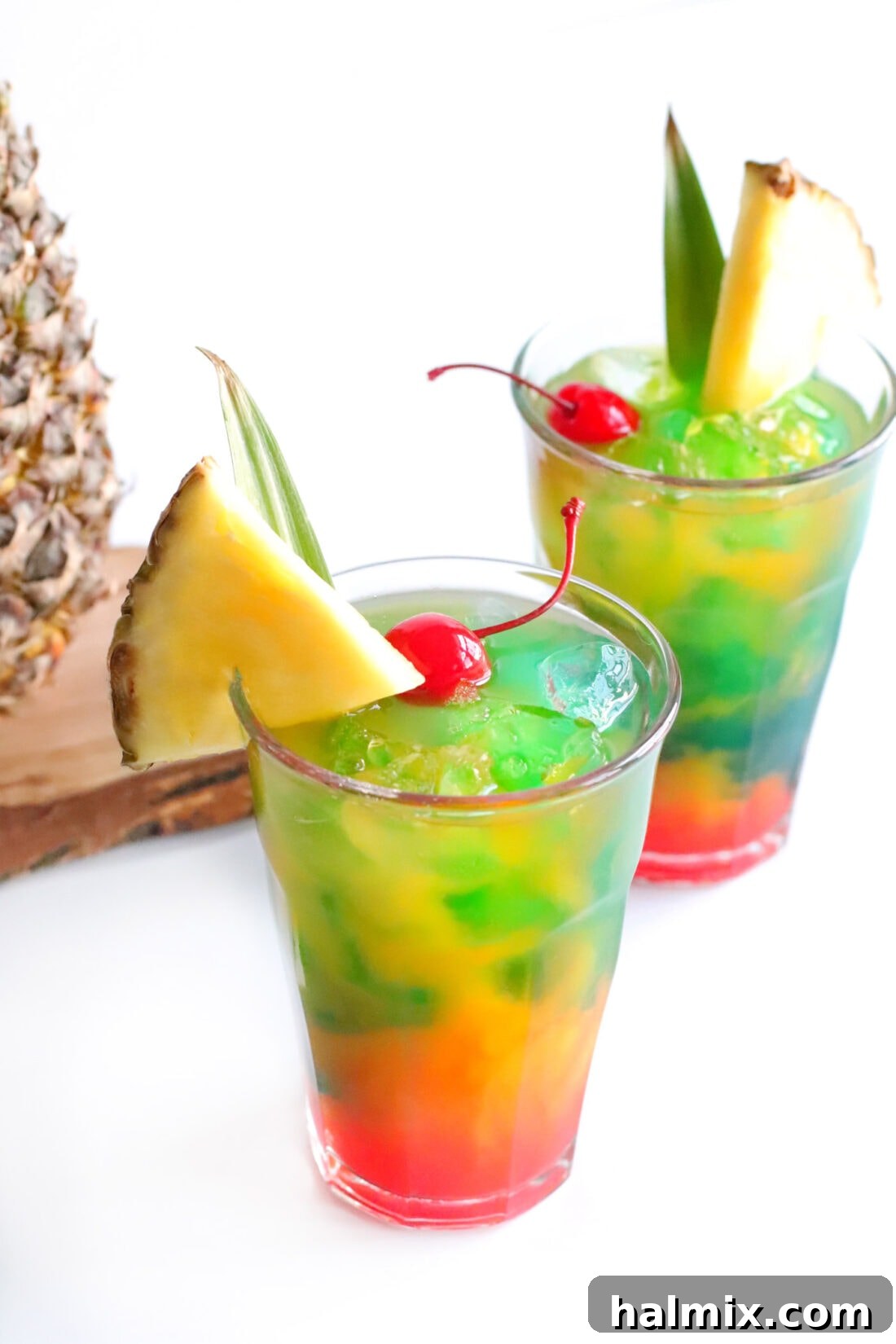 Two Blue Hawaiian Mai Tai drinks garnished with a pineapple wedge and cherry, ready to be enjoyed.