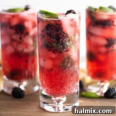 Three finished Blackberry Mojito cocktails in tall glasses, garnished with fresh fruit and mint, ready to be served.