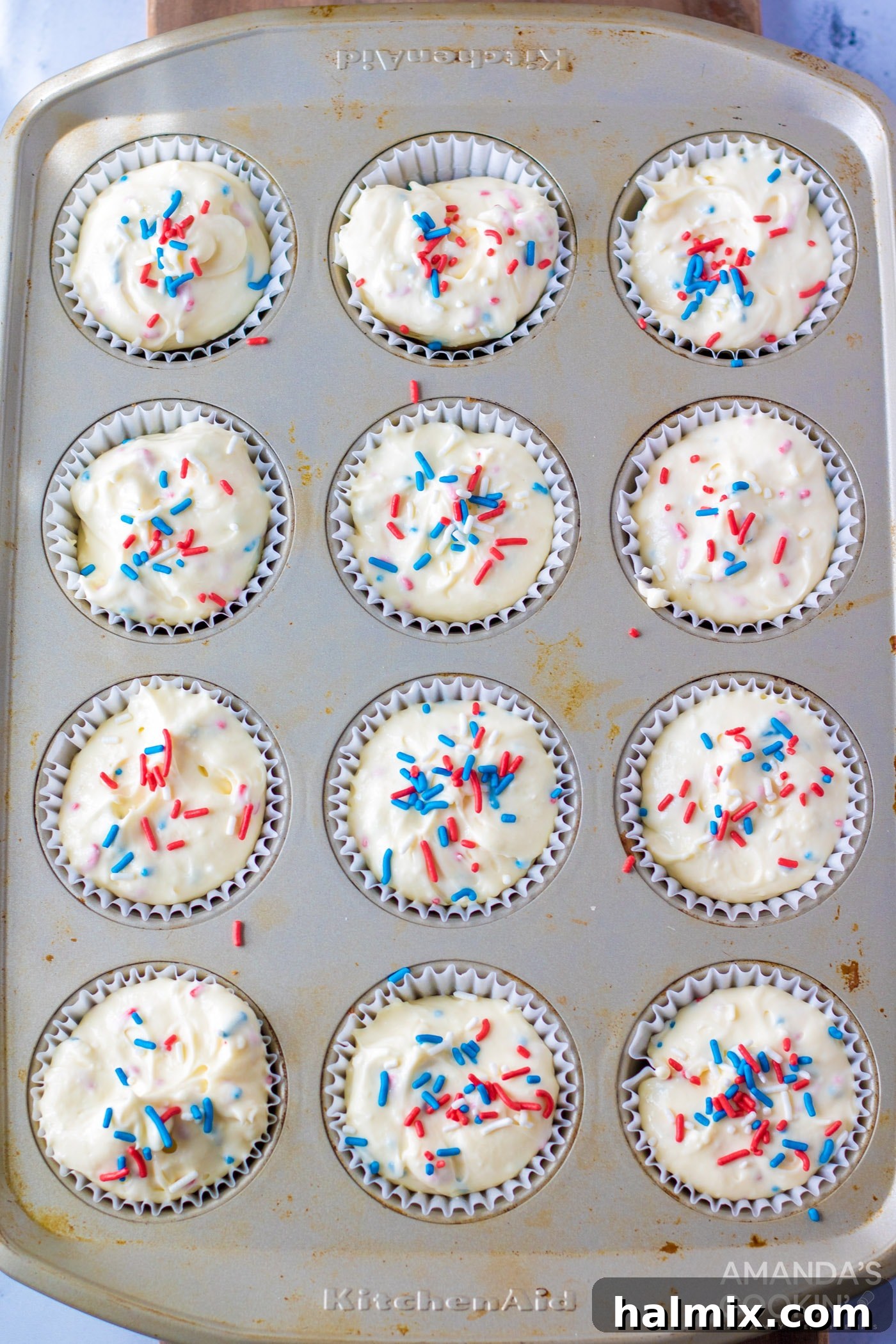 Mini cheesecake batter in a muffin tin with sprinkles