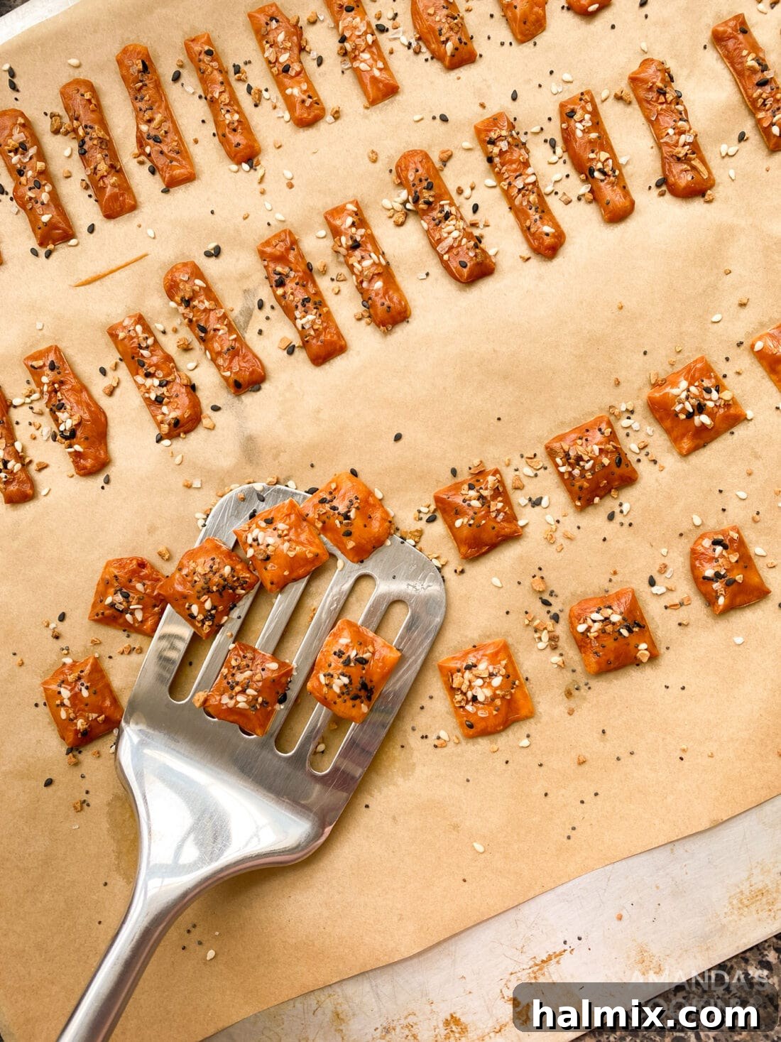 Spatula lifting golden-brown keto cheese crackers from a baking sheet, showcasing their perfect crispness.
