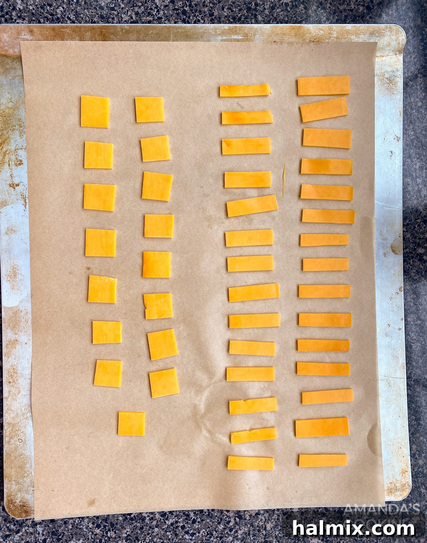 Neatly cut cheese pieces arranged on a parchment-lined baking sheet, ready for seasoning.