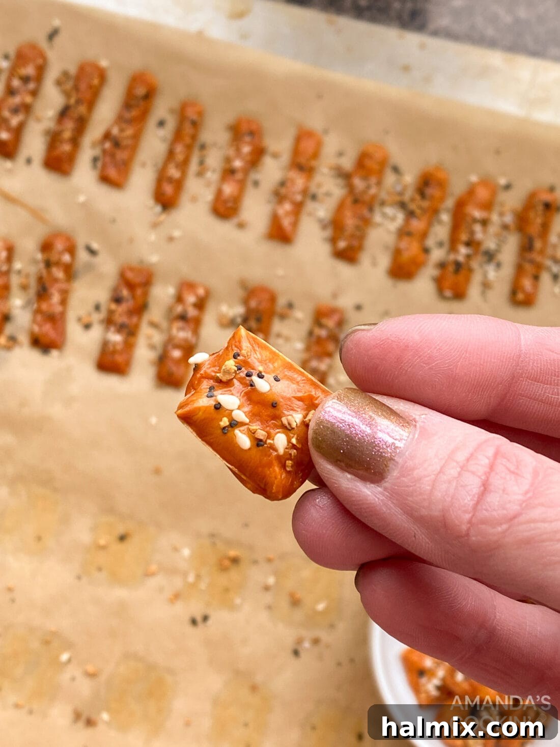 Hand holding a perfectly golden-brown keto cheese cracker, ready for a bite.