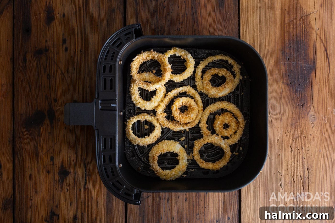 Golden Air-Fried Onion Rings 7 Breaded onion rings arranged in a single layer inside an air fryer basket, ready for cooking.