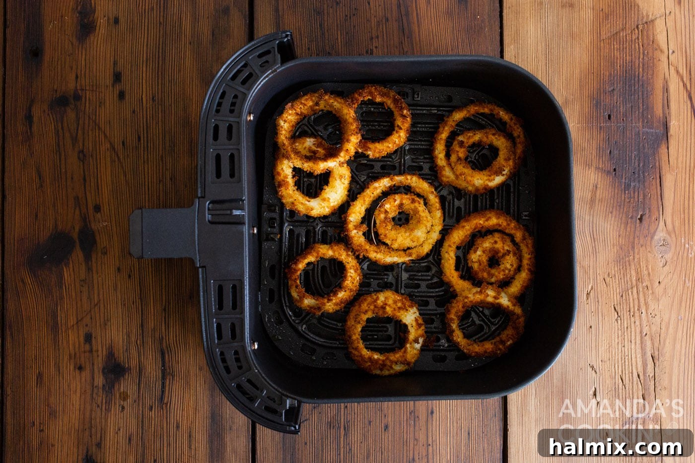 Golden Air-Fried Onion Rings 8 Crispy, golden-brown onion rings cooking inside an air fryer basket.