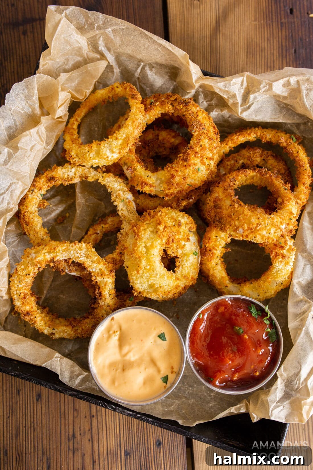Golden Air-Fried Onion Rings 9 Air Fryer Onion Rings served on a tray lined with parchment paper, accompanied by a small dish of dipping sauce.