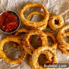Air Fryer Onion Rings on parchment paper with a dish of ketchup, ready to be enjoyed.