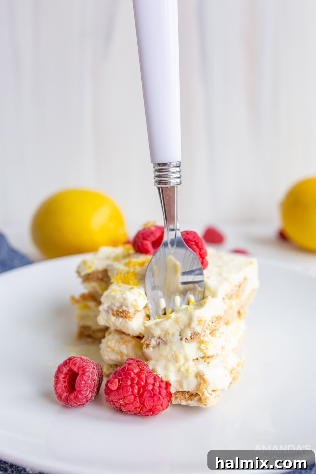 Refreshing Lemon Icebox Cake 11 close-up of a fork taking a bite from a slice of lemon icebox cake, highlighting the creamy texture