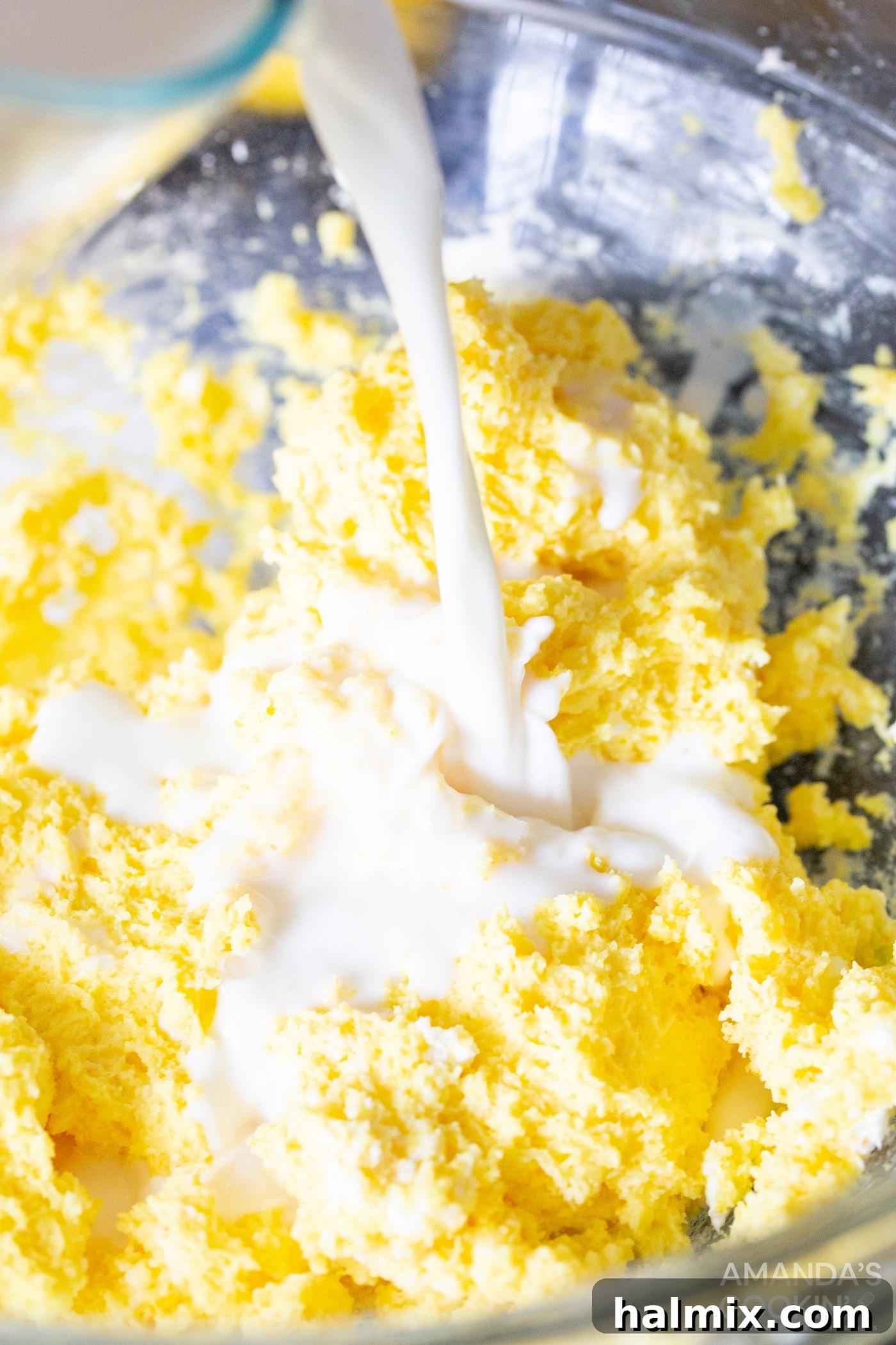 Refreshing Lemon Icebox Cake 7 milk being poured slowly into the lemon pudding and cream cheese mixture