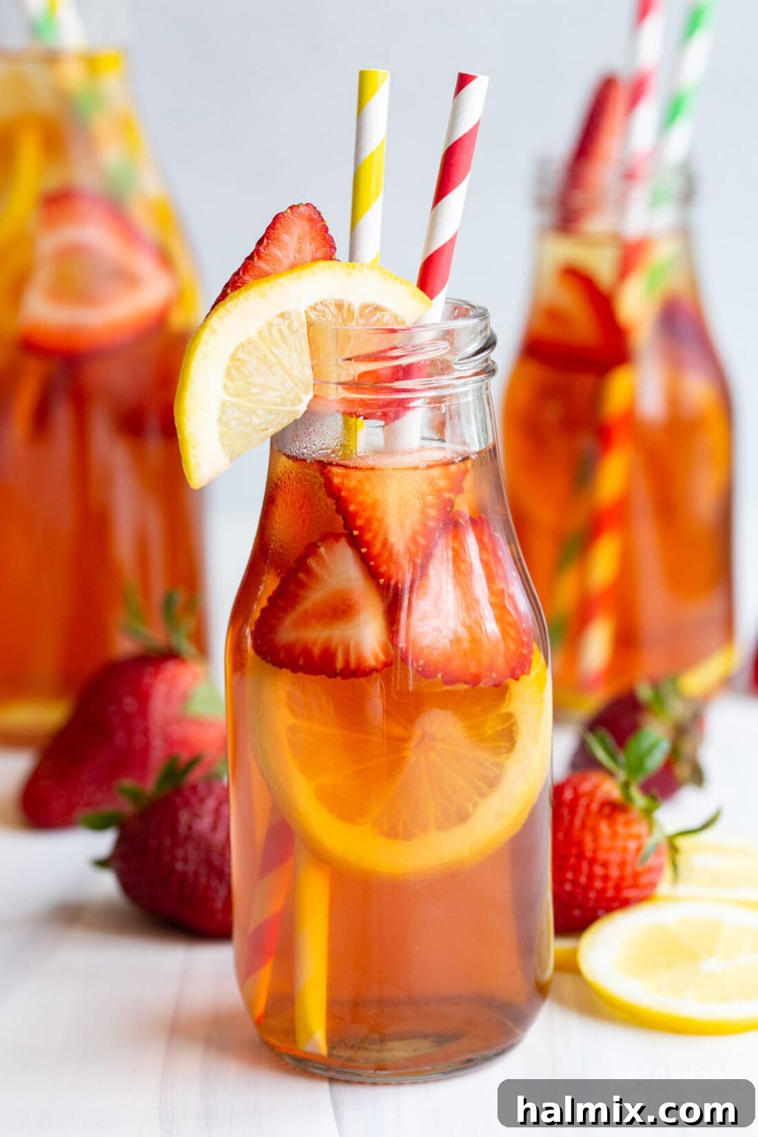A bottle of homemade strawberry sweet tea with fresh strawberries and lemon slices