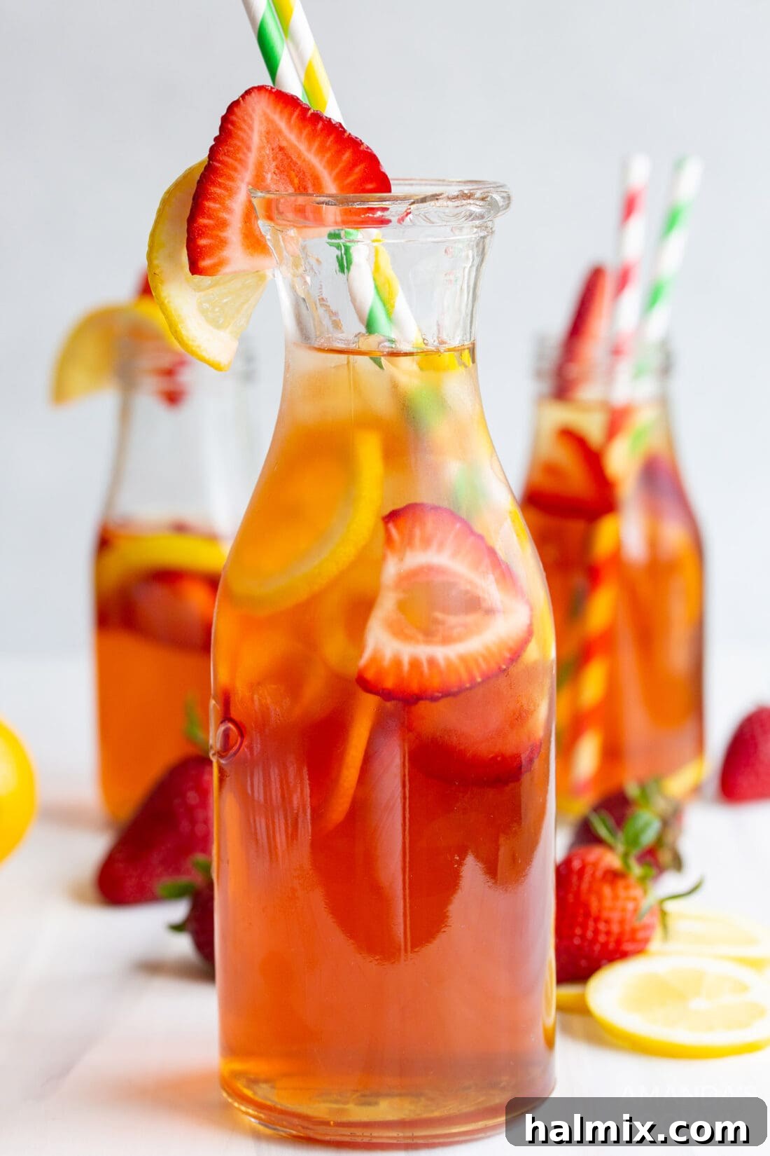 Close-up of strawberry sweet tea in a glass bottle, garnished with fresh strawberries and lemon