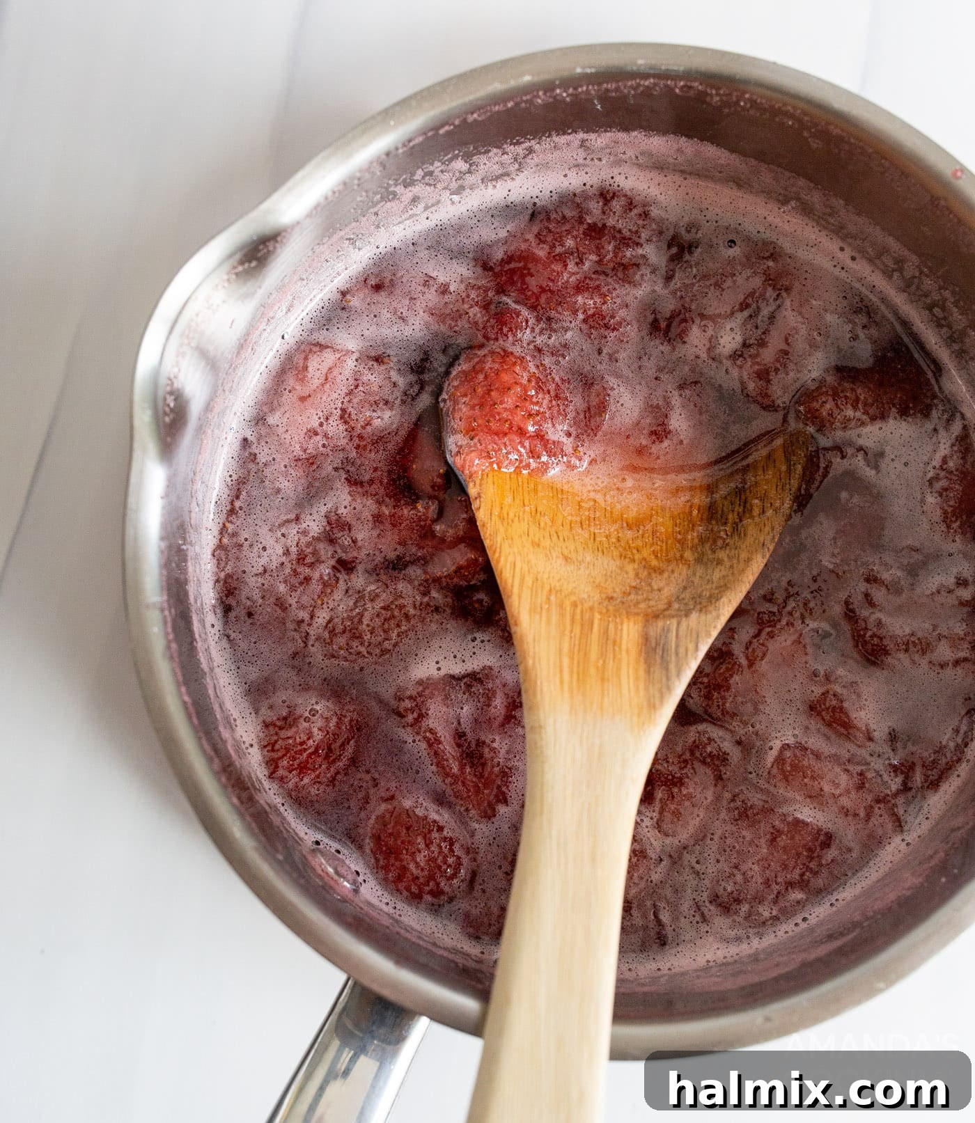 Strawberry simple syrup bubbling gently in a saucepan