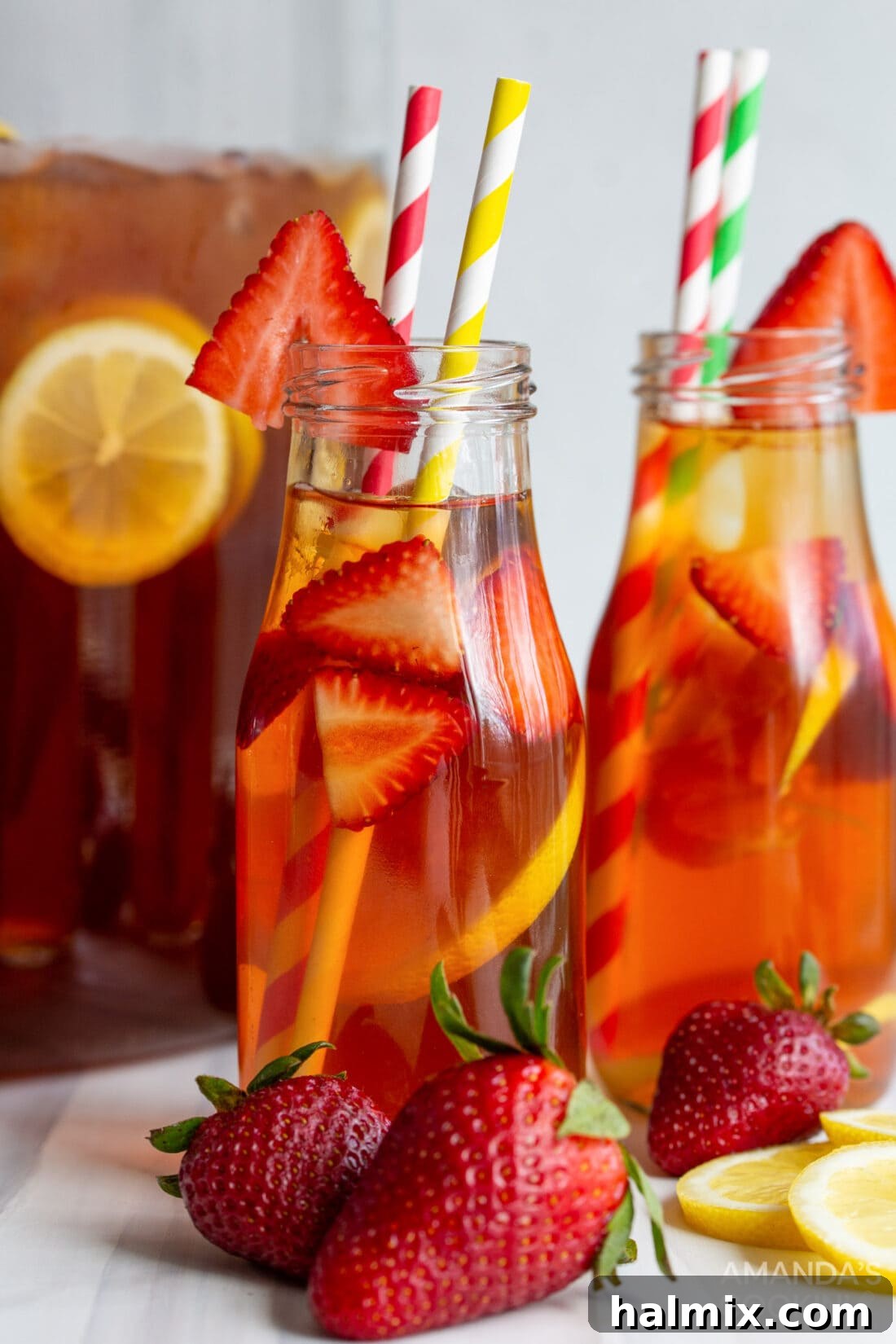 A large pitcher of strawberry sweet tea with ice, lemon, and strawberries, ready to serve