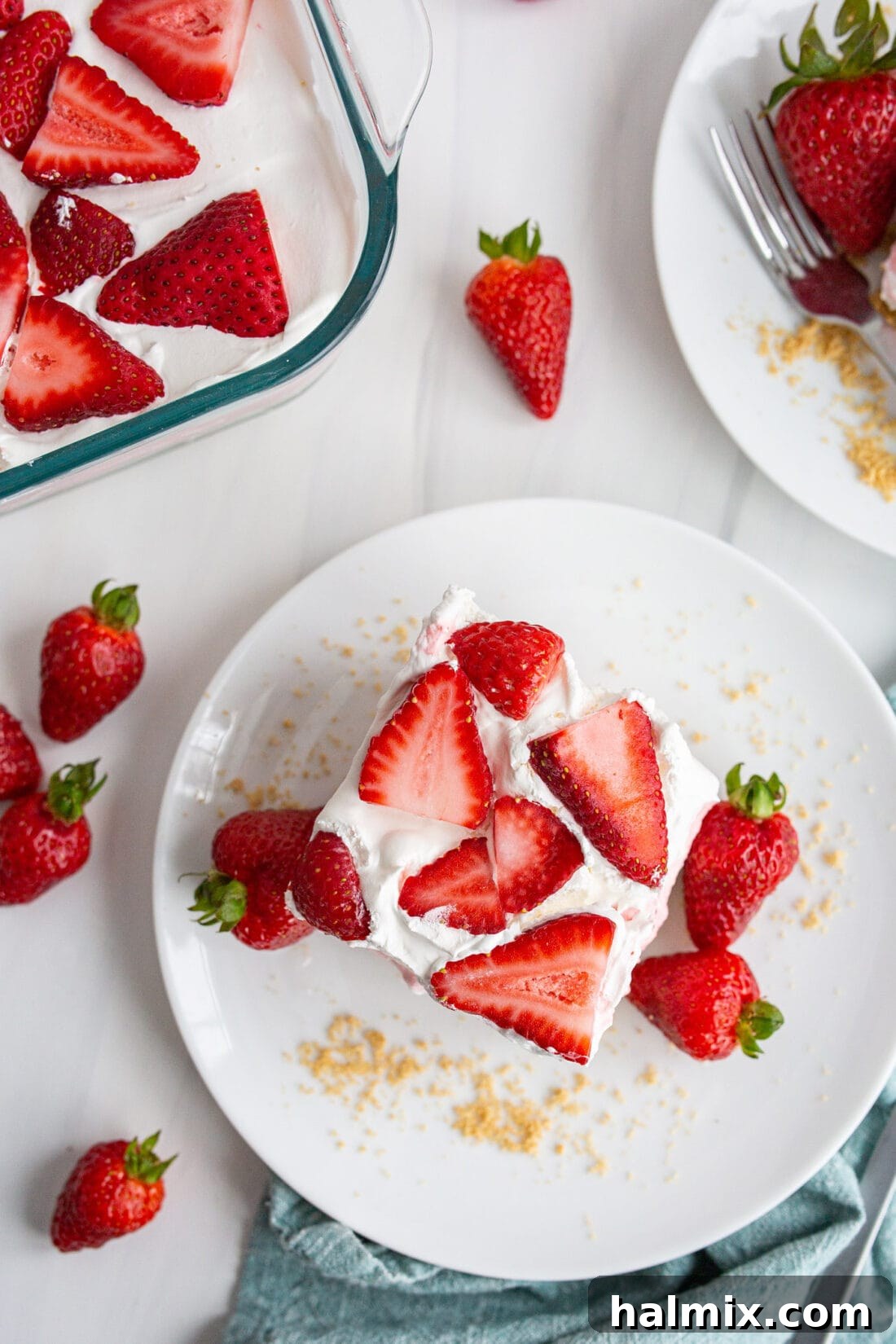 Overhead photo of a square slice of Strawberry Lasagna on a white plate, highlighting the creamy layers and fresh strawberry garnish.