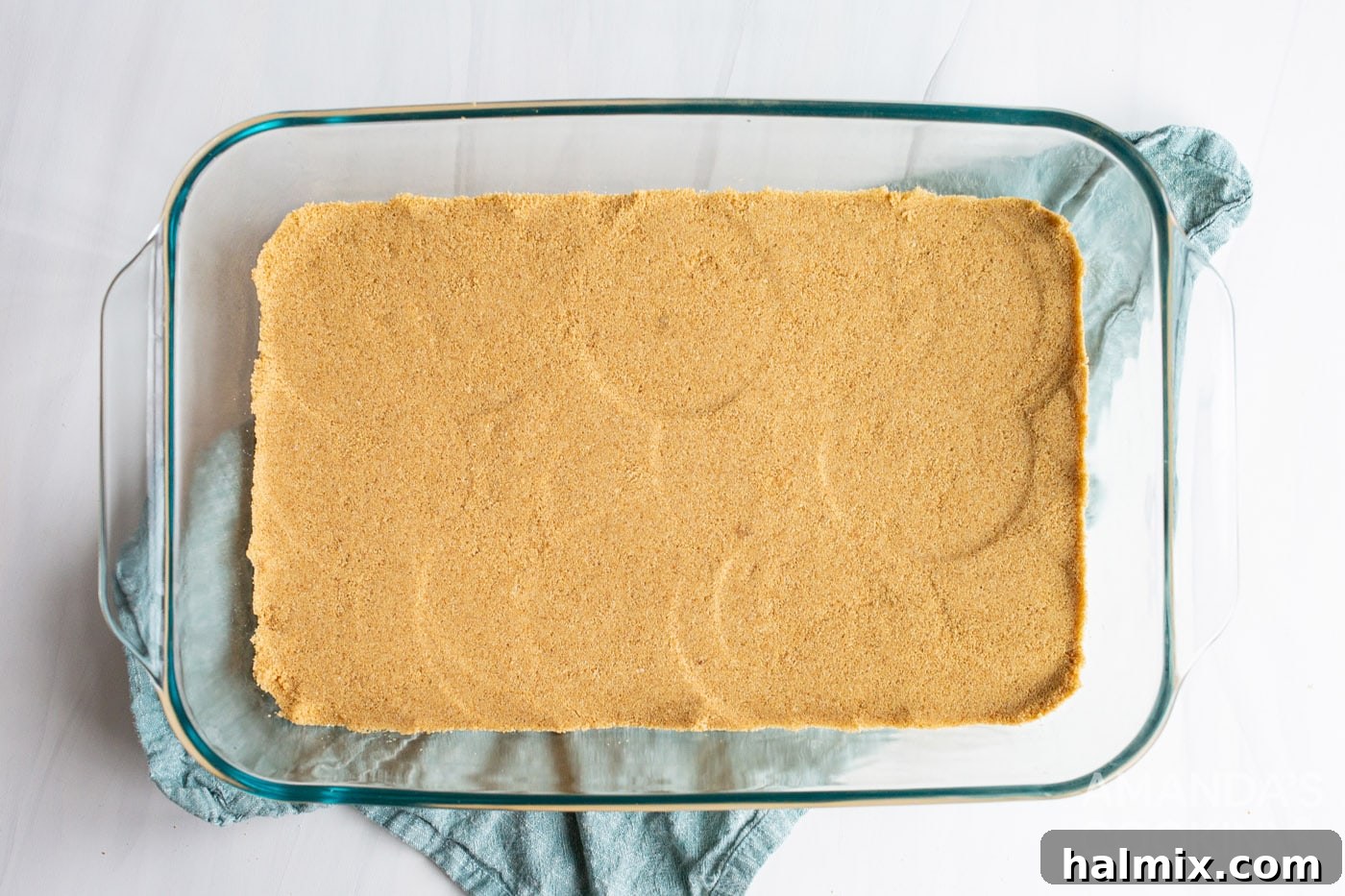 Graham cracker mixture pressed into an even layer in a 9x13 baking dish, forming the crust