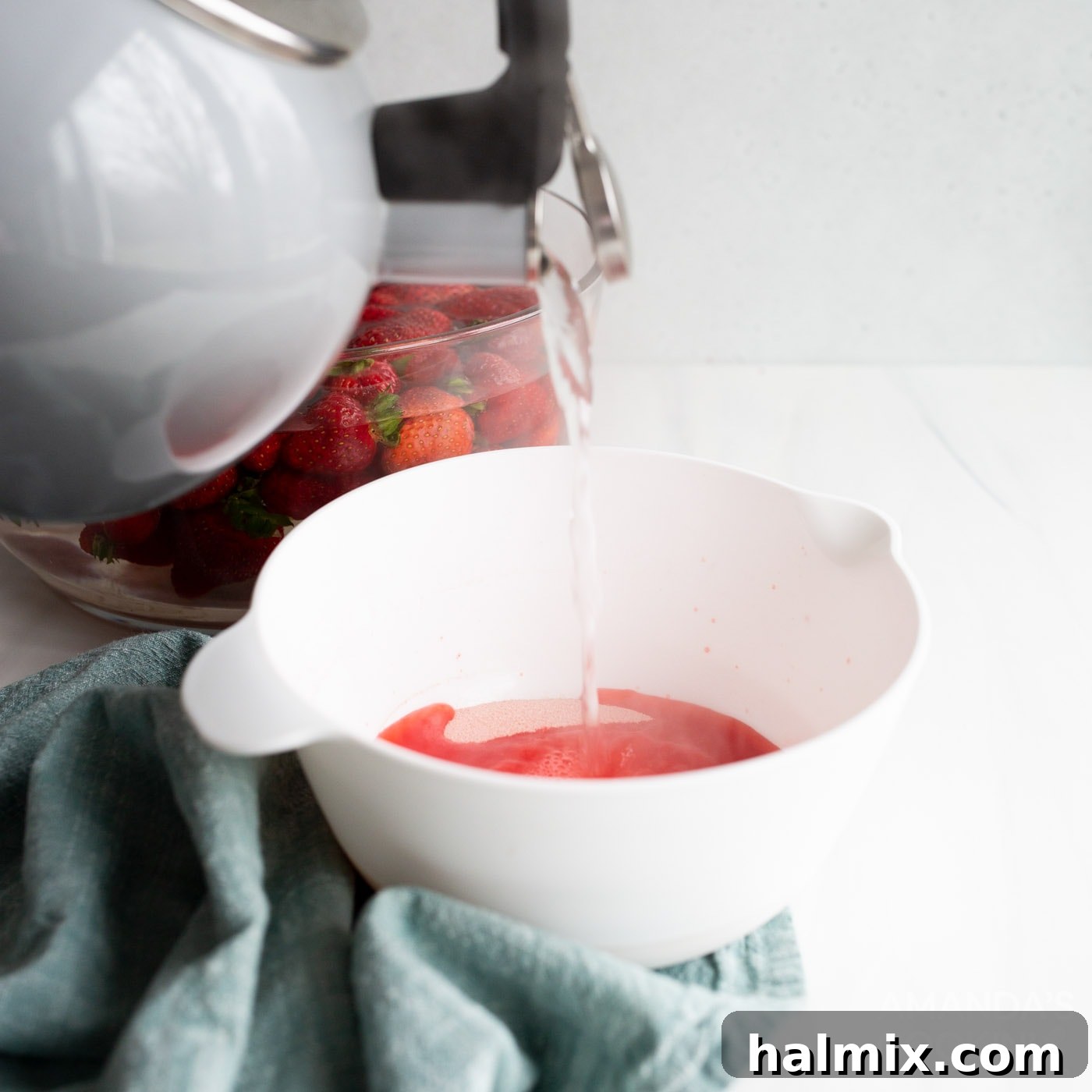 Strawberry jello powder dissolving in boiling hot water in a mixing bowl