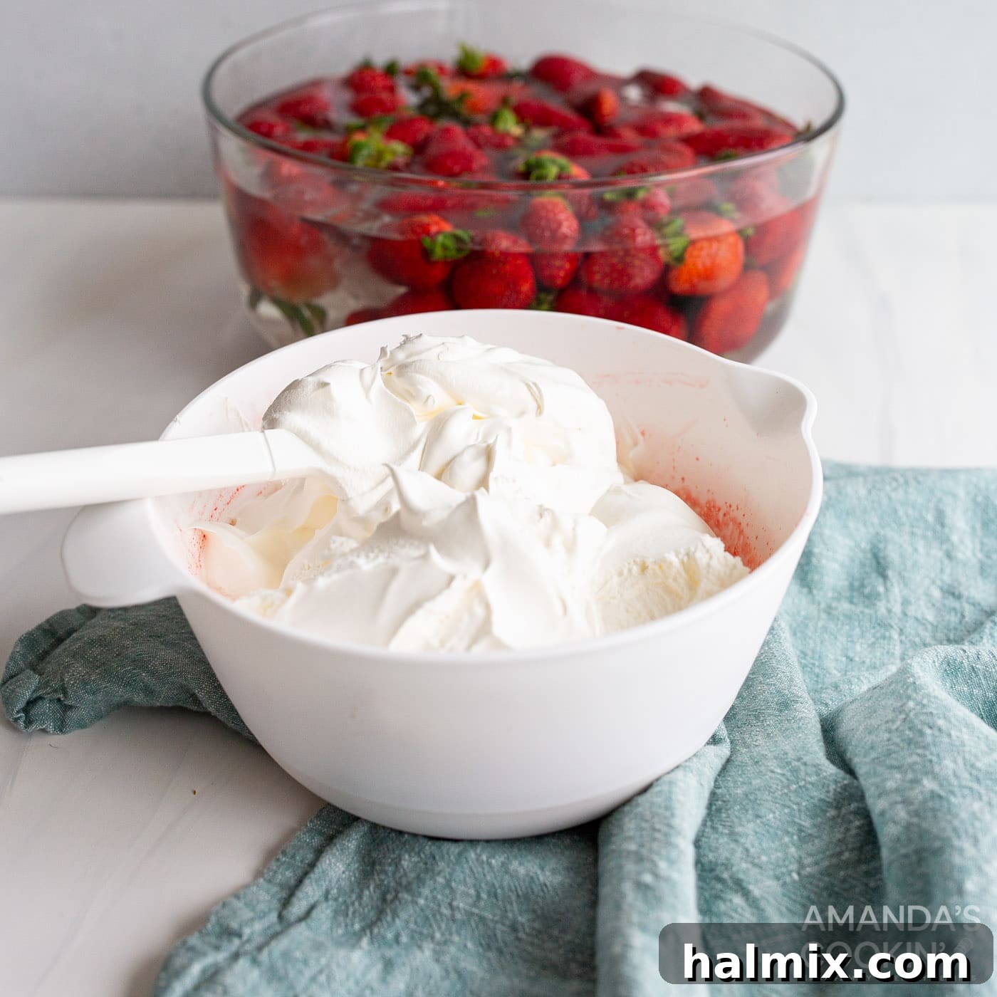 Folding Cool Whip into a cooled and slightly thickened strawberry jello mixture with chopped strawberries