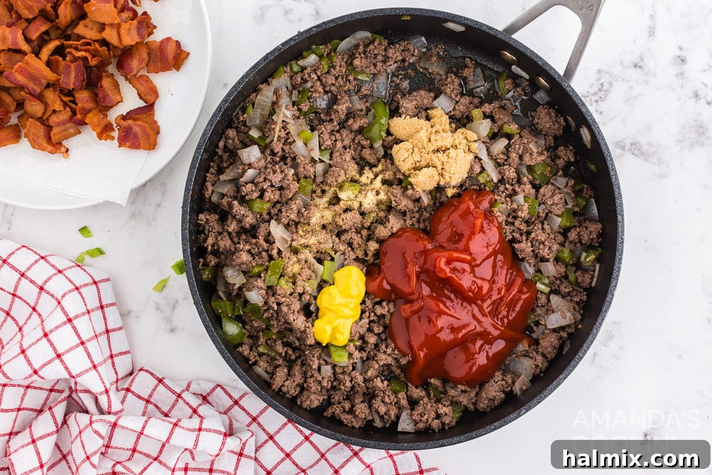 Ketchup and mustard being added to the browned ground beef mixture in the pan