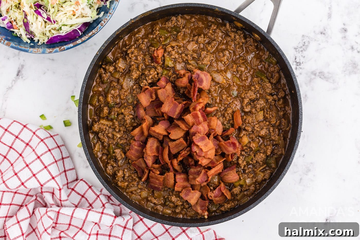 Cooked bacon being added back into the sloppy joe mixture in the pan