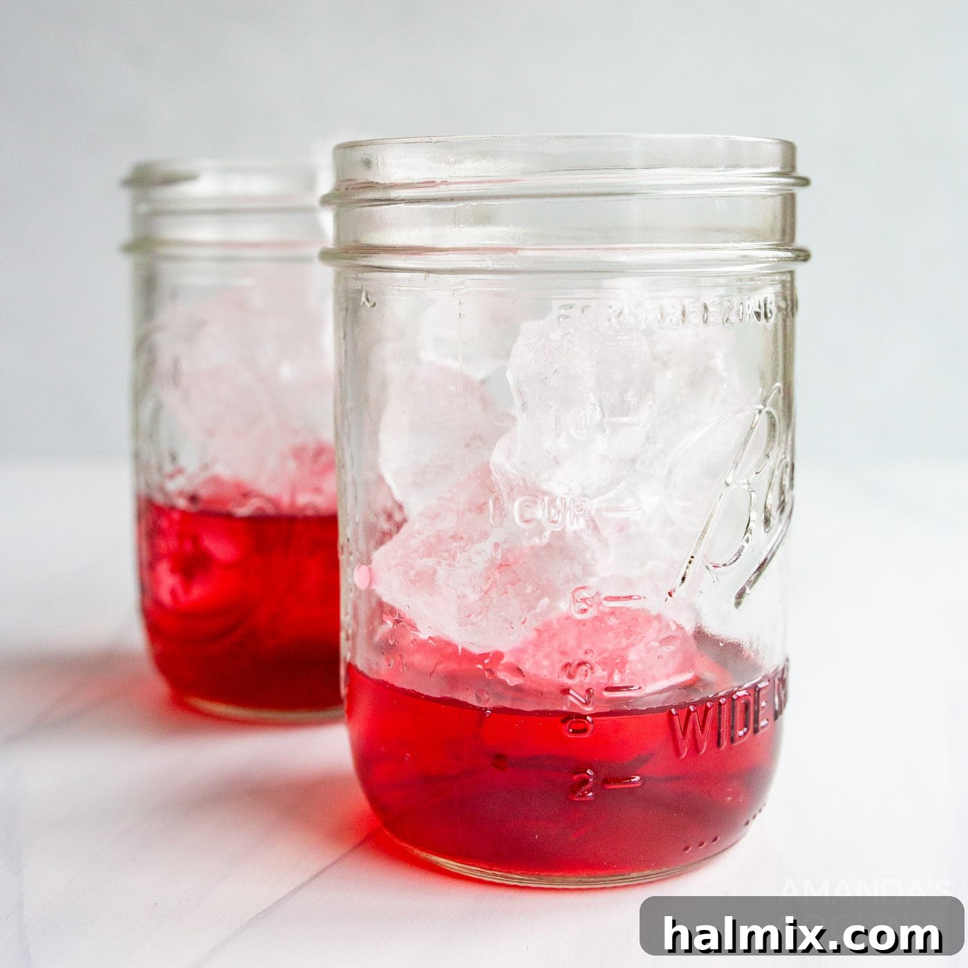 Mason jar filled with ice and a vibrant red layer of cran-raspberry juice