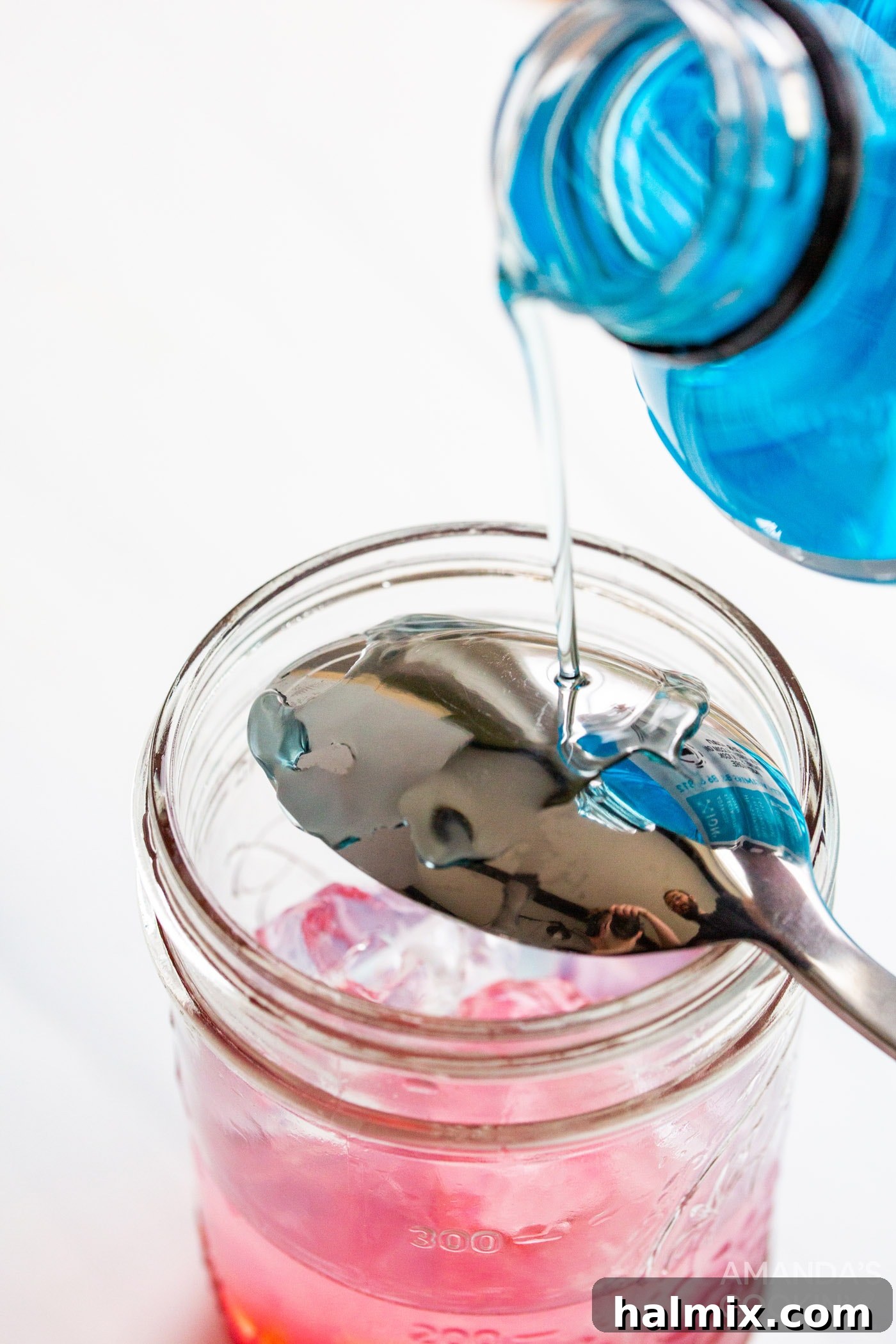 Pouring blue Powerade Zero over the back of an upside-down spoon to create the top layer