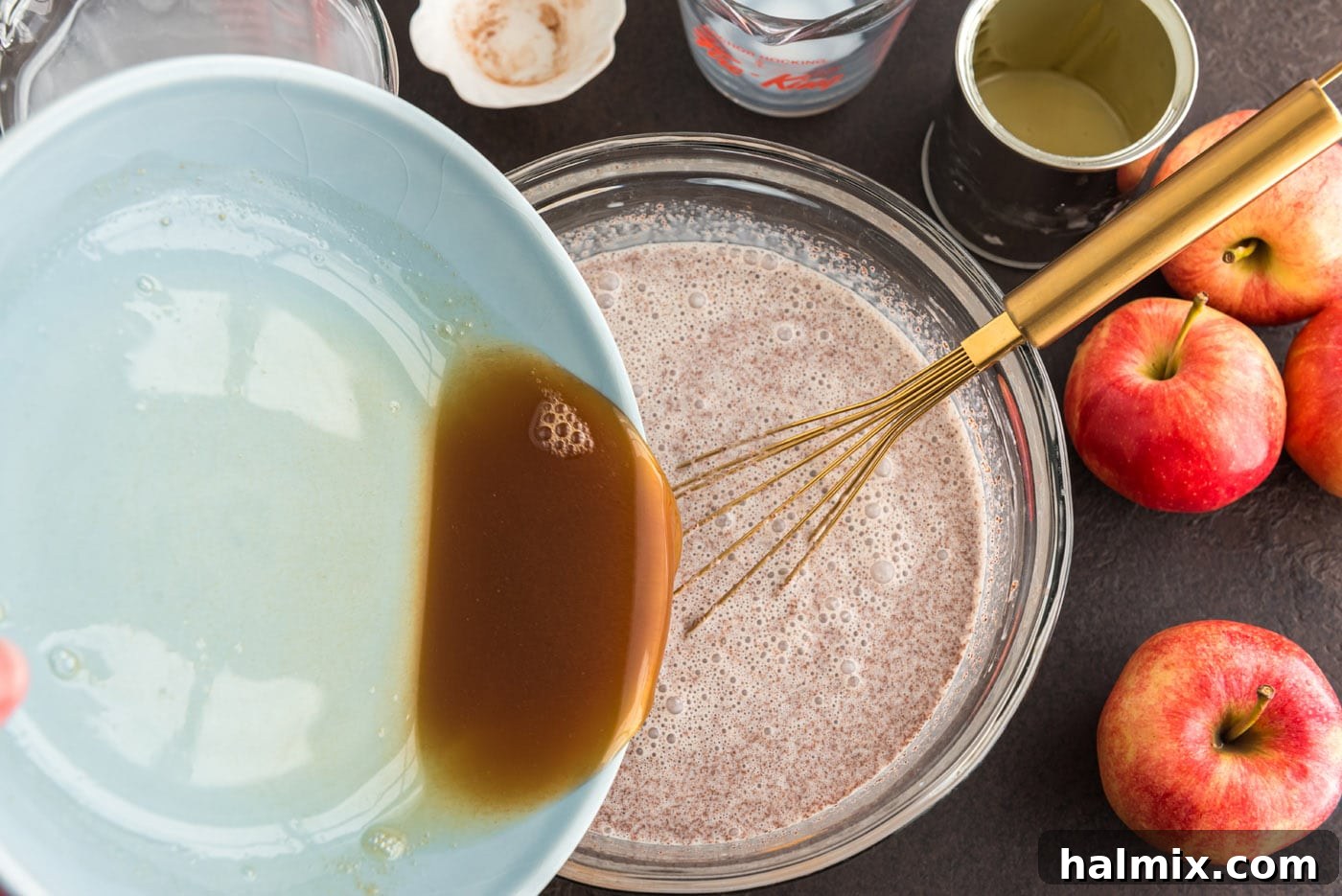 The cooled, reduced apple cider being carefully poured into the large mixing bowl containing the whisked cream and milk base, ready for final mixing.