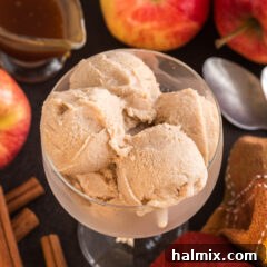 A close-up view of multiple scoops of homemade Apple Cider Ice Cream presented beautifully in a sundae dish, with a hint of caramel sauce, highlighting its luscious texture.