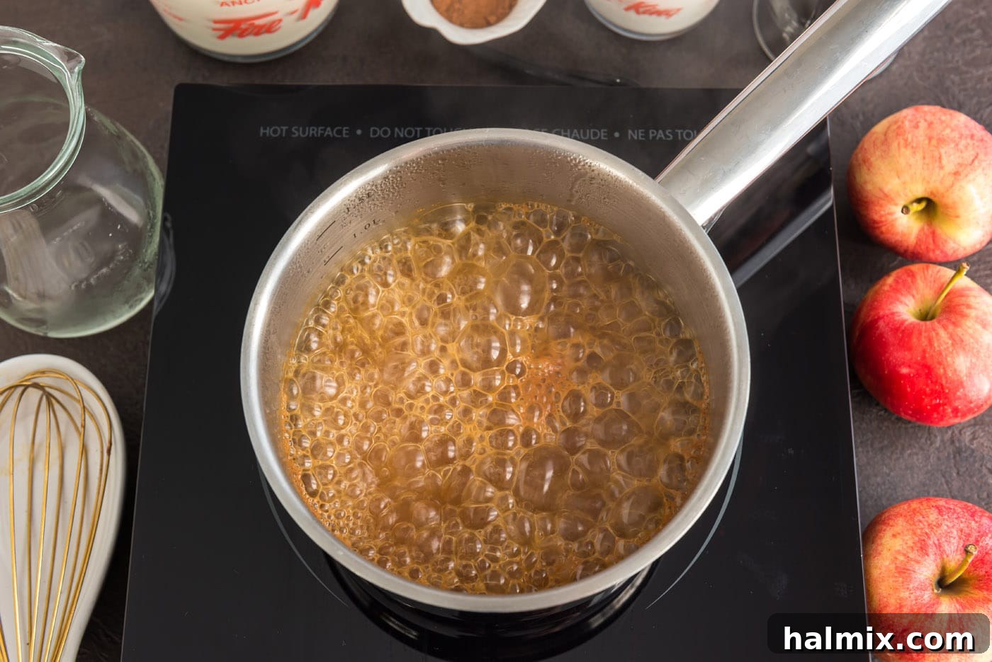 Vigorously boiling apple cider in a saucepan on a stovetop, with steam rising, illustrating the crucial reduction stage of the recipe.