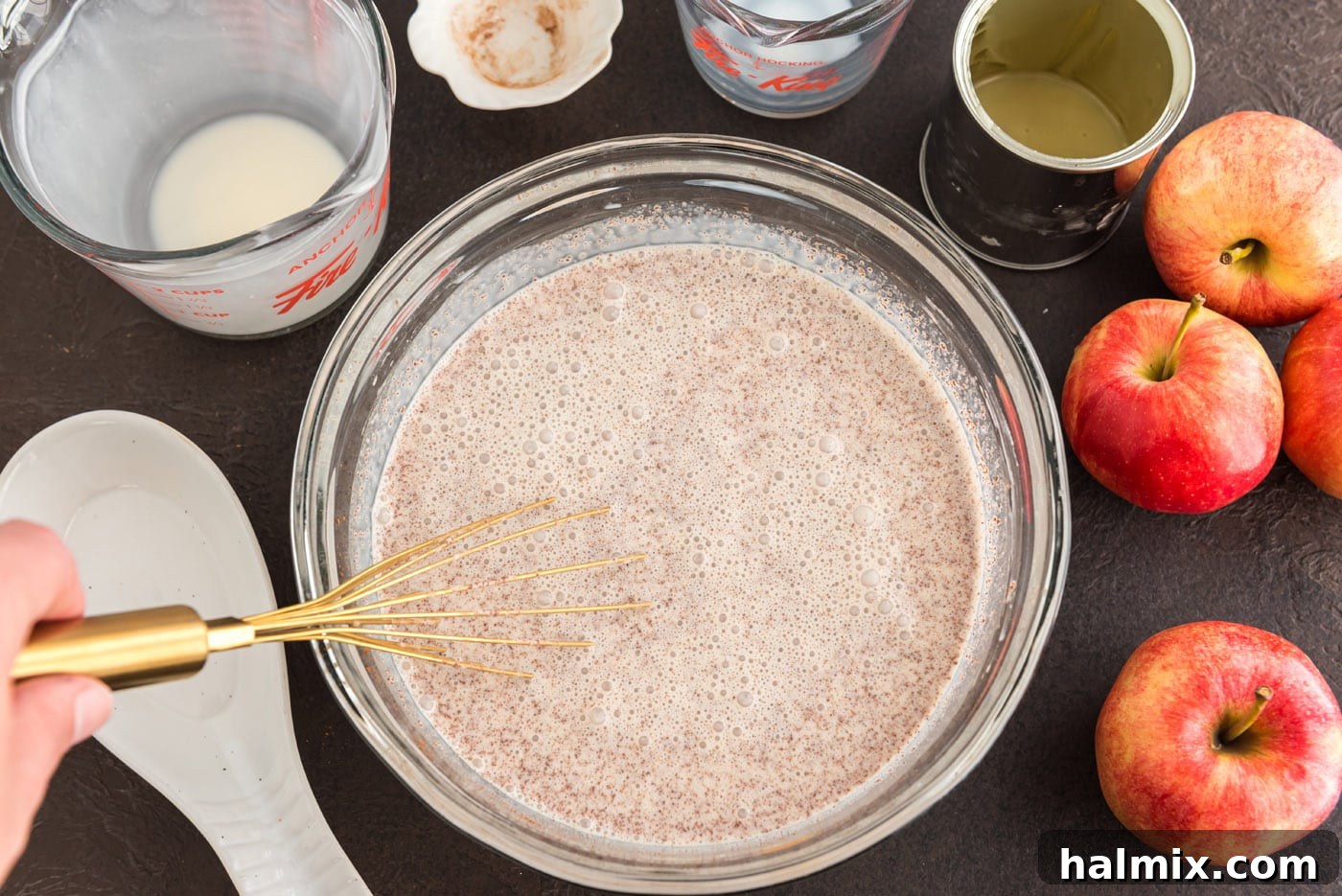 A close-up view of the cream, sweetened condensed milk, and cinnamon mixture being vigorously whisked in a large bowl, creating a smooth and uniform ice cream base.