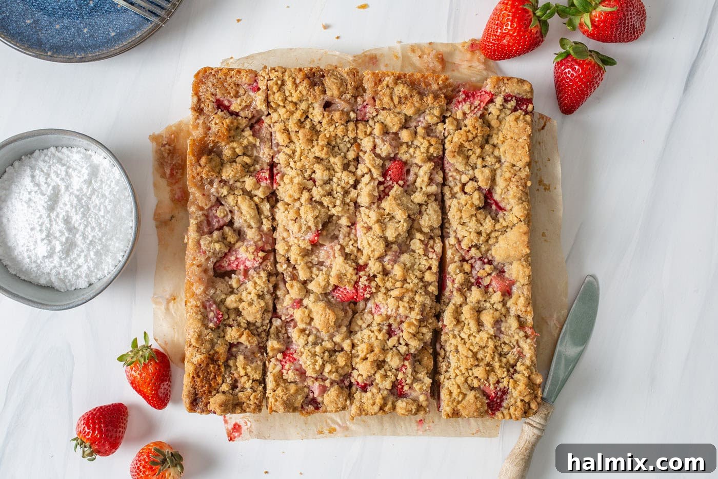 A batch of freshly baked and perfectly sliced strawberry rhubarb crumble bars, arranged neatly on a cutting board