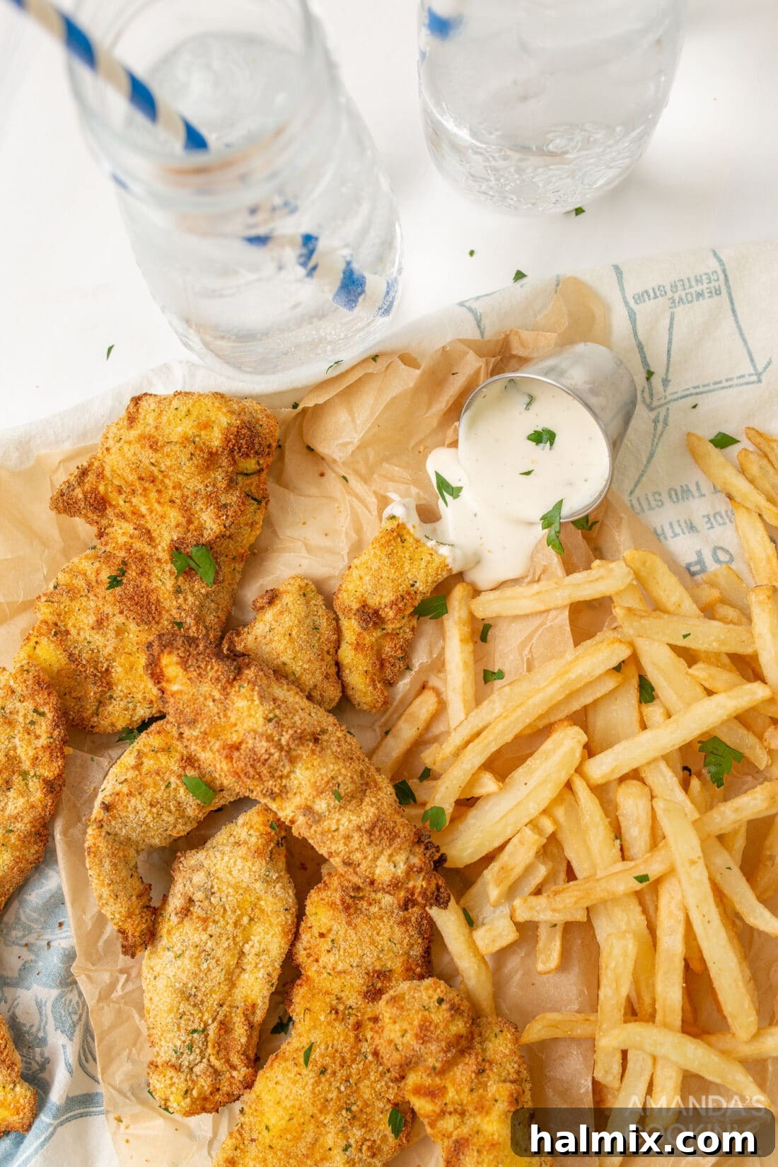 Golden brown air fryer chicken tenders arranged neatly on parchment paper with a side of fries