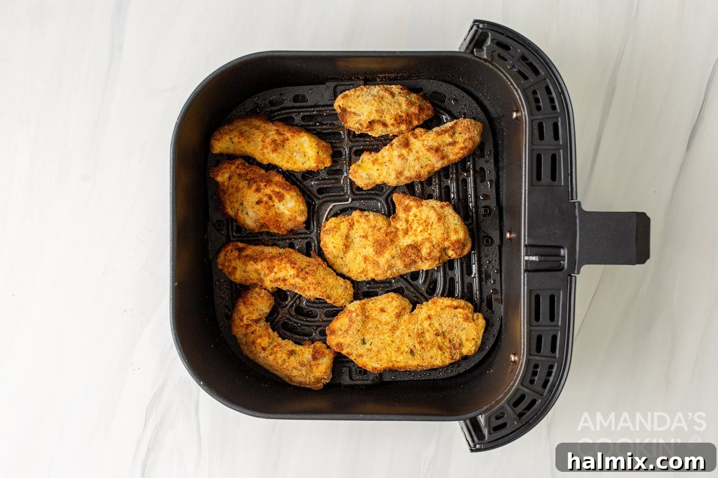 Air fryer basket filled with perfectly golden and crispy breaded chicken tenders, hot and ready to serve