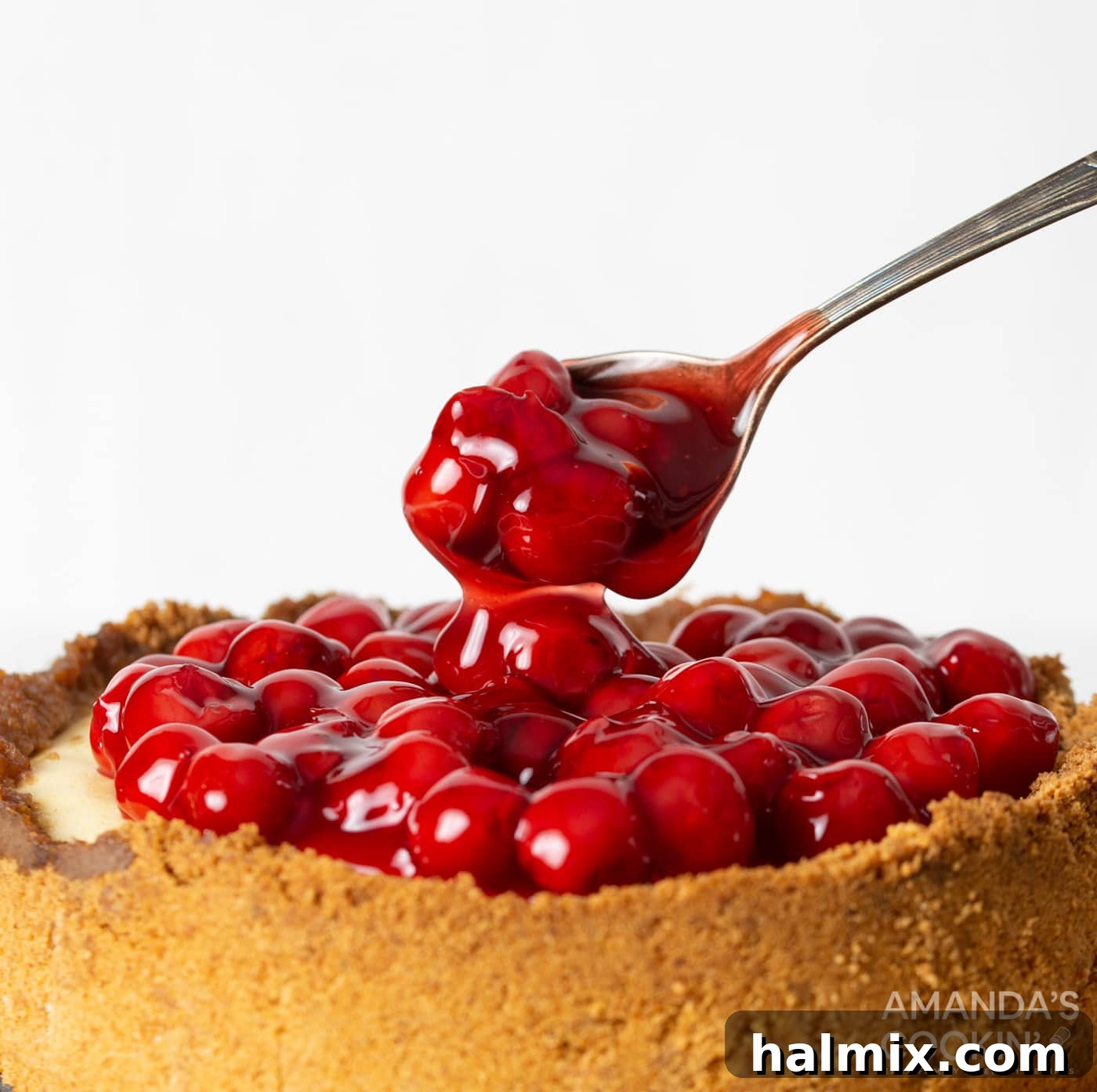 spoon with cherry pie filling on cheesecake
