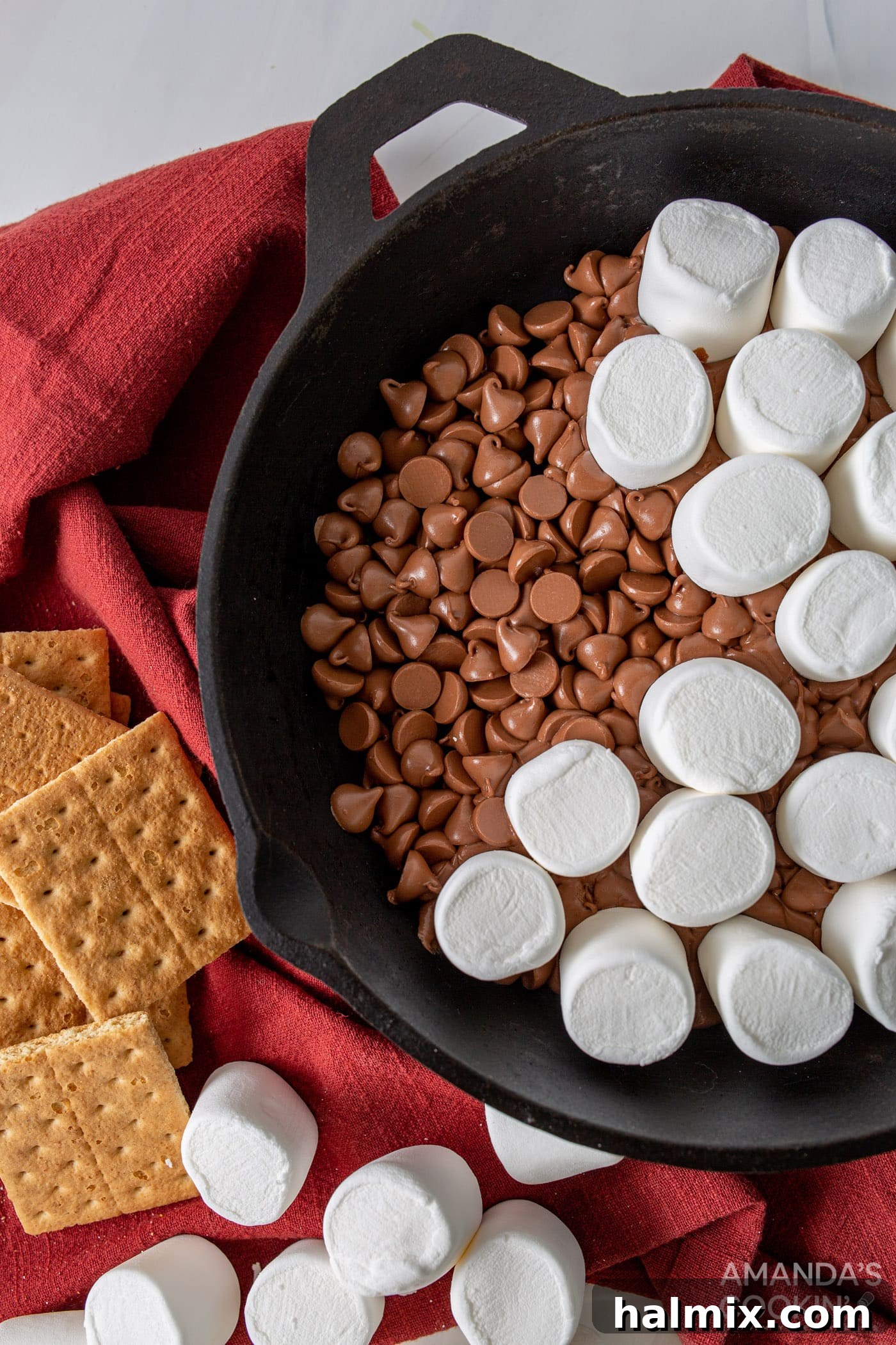 Gooey S'mores Skillet 6 marshmallows placed on top of melted chocolate chips in a skillet