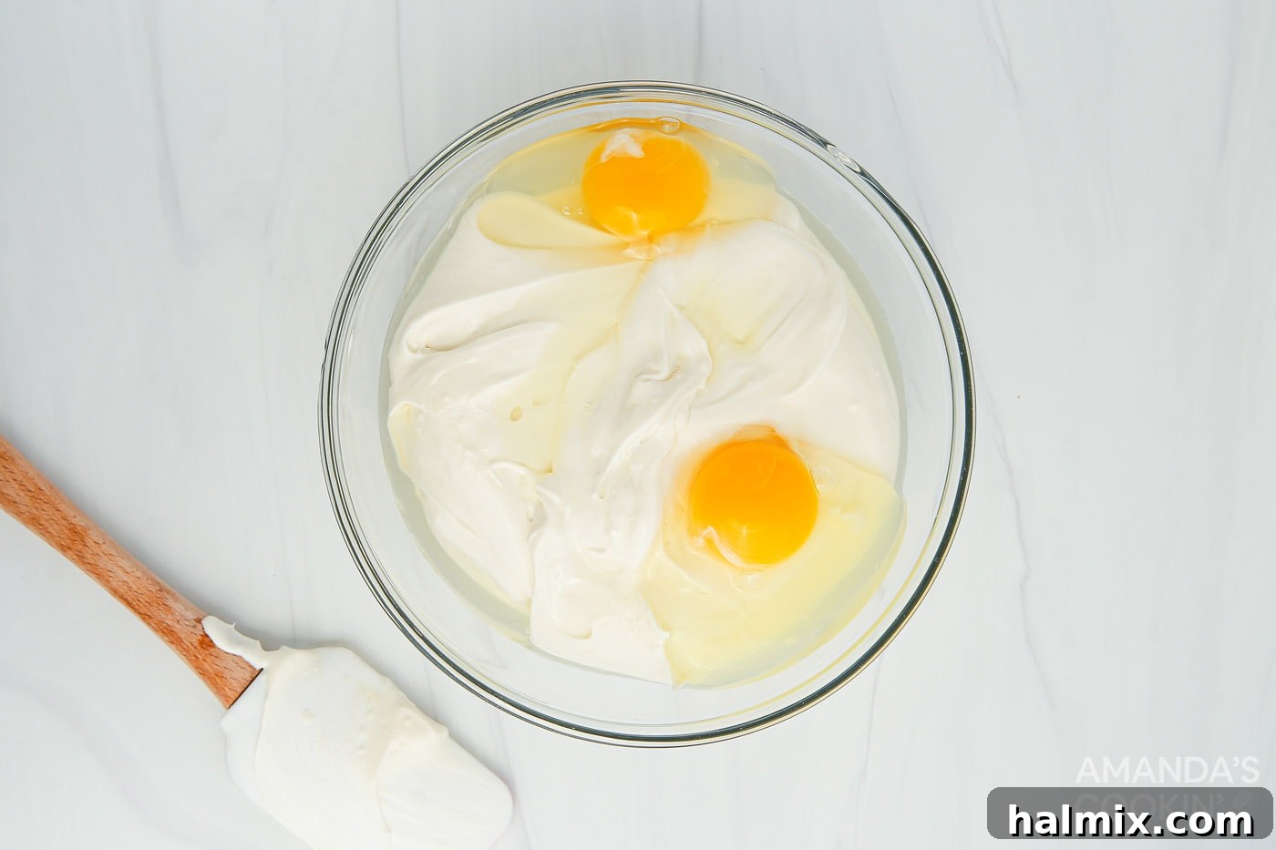 eggs in a mixing bowl with cream cheese and sour cream mixture