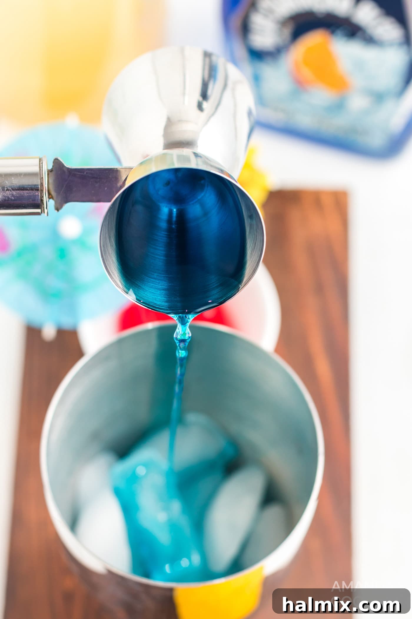 Azure Escape 6 Pouring blue Curacao into a cocktail shaker with ice.