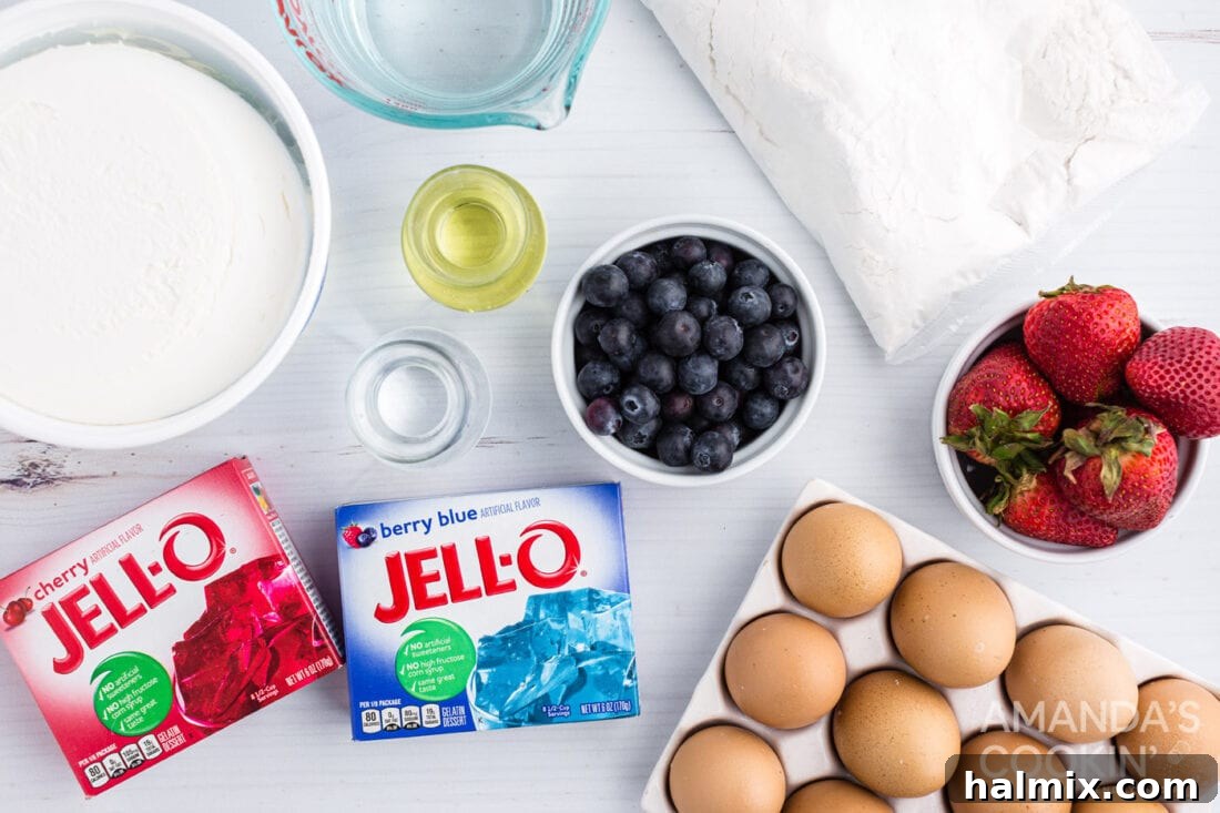 A flat lay photograph showcasing all ingredients for the patriotic American flag poke cake: cake mix, Jell-O boxes, Cool Whip, strawberries, and blueberries.