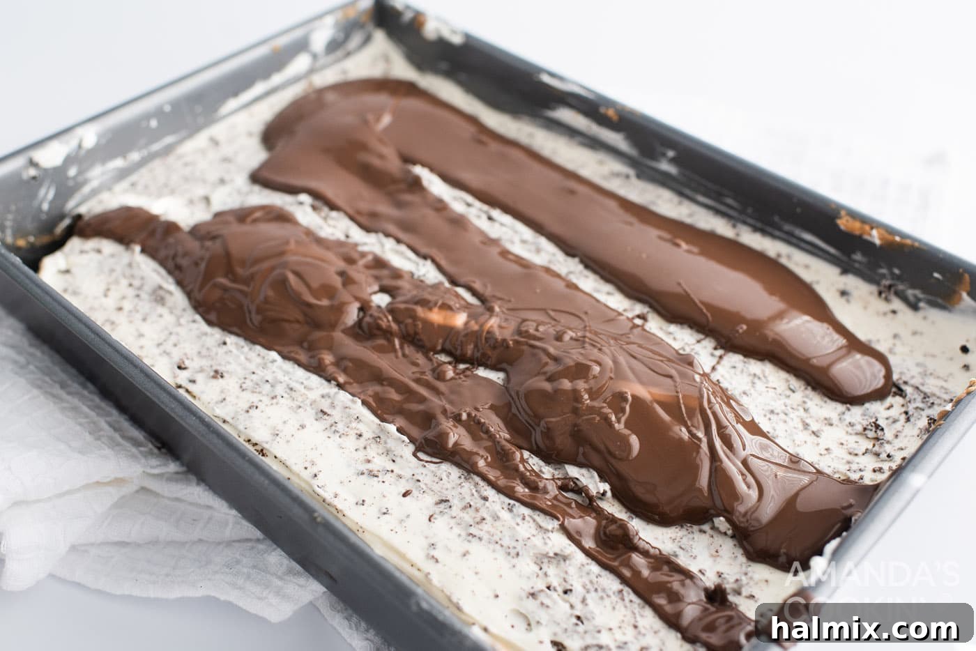 Glossy chocolate ganache topping poured over the Oreo cheesecake in a pan