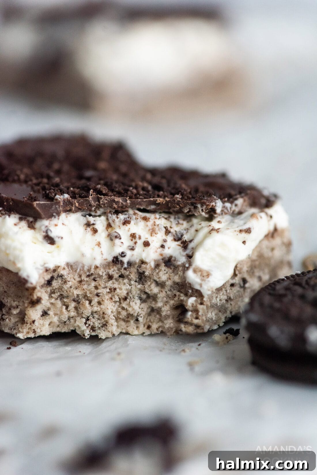 A single Oreo cheesecake bar with a bite taken out, showing the layers