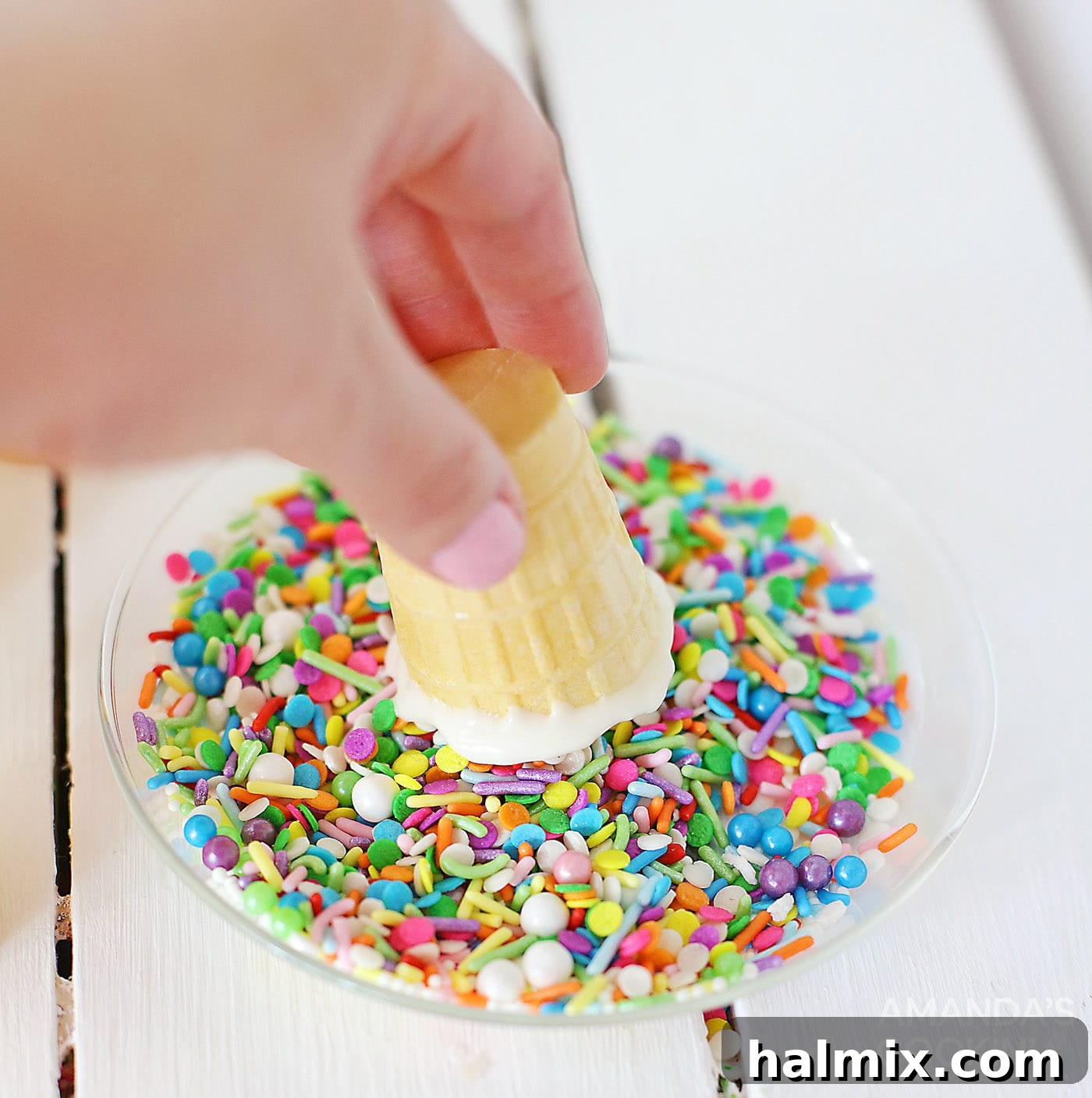 Dipping chocolate-coated ice cream cone in sprinkles