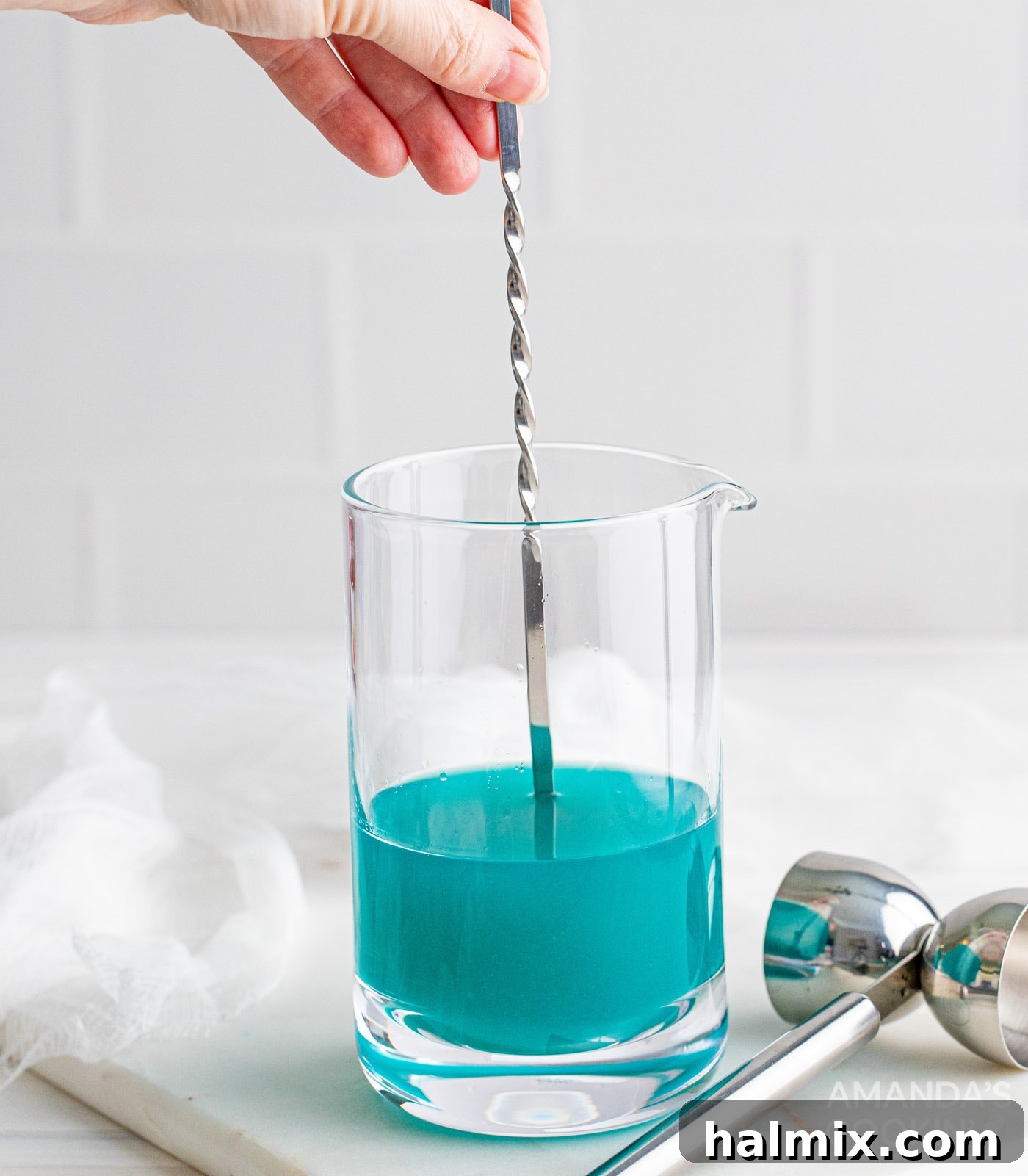 Neptune's Kiss Cocktail 7 Stirring the blend of coconut water, pineapple juice, blue curacao, and coconut rum in a mixing glass.