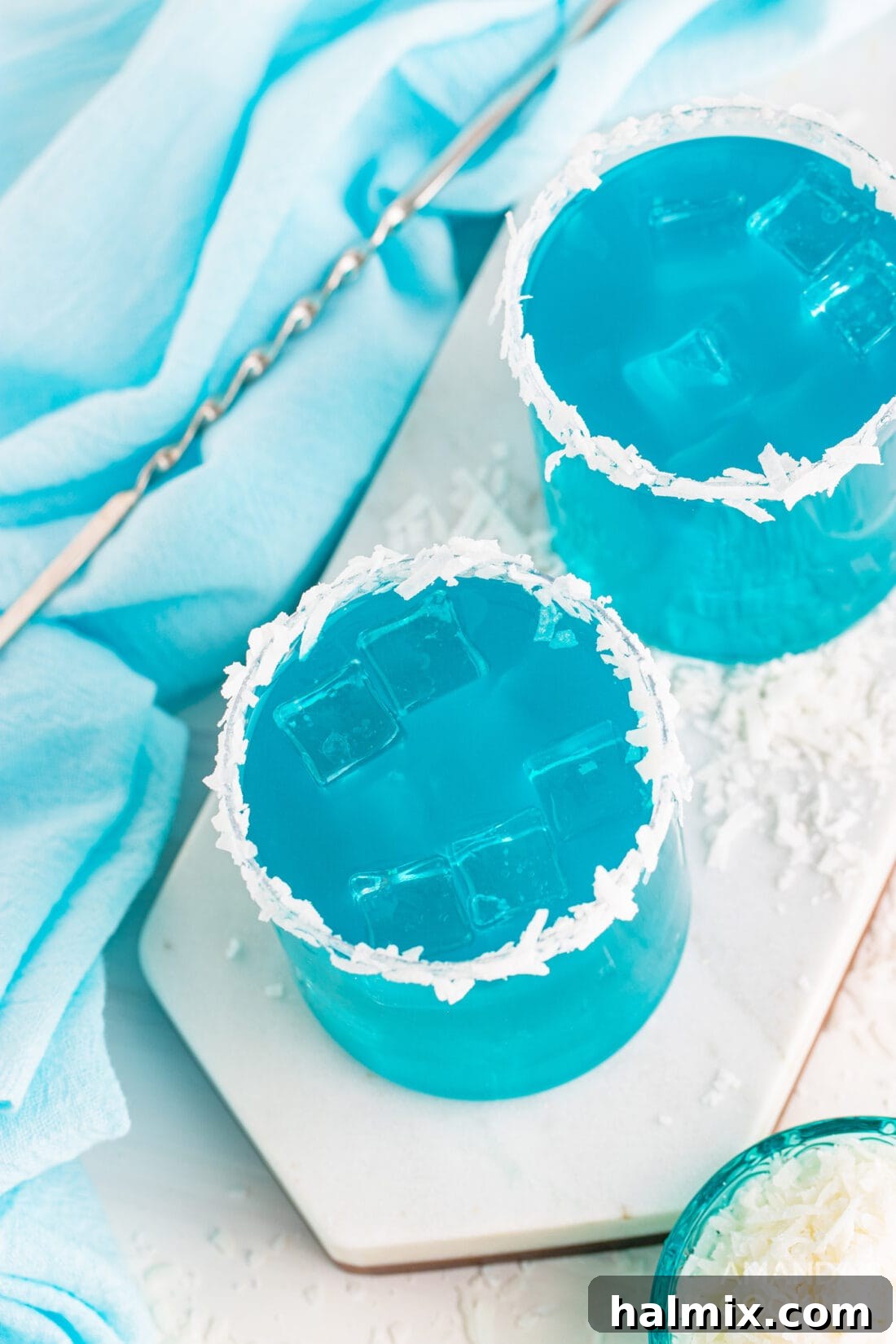 Neptune's Kiss Cocktail 9 Overhead view of two glasses of Ocean Water Cocktail, beautifully garnished, reflecting the tropical blue hues.